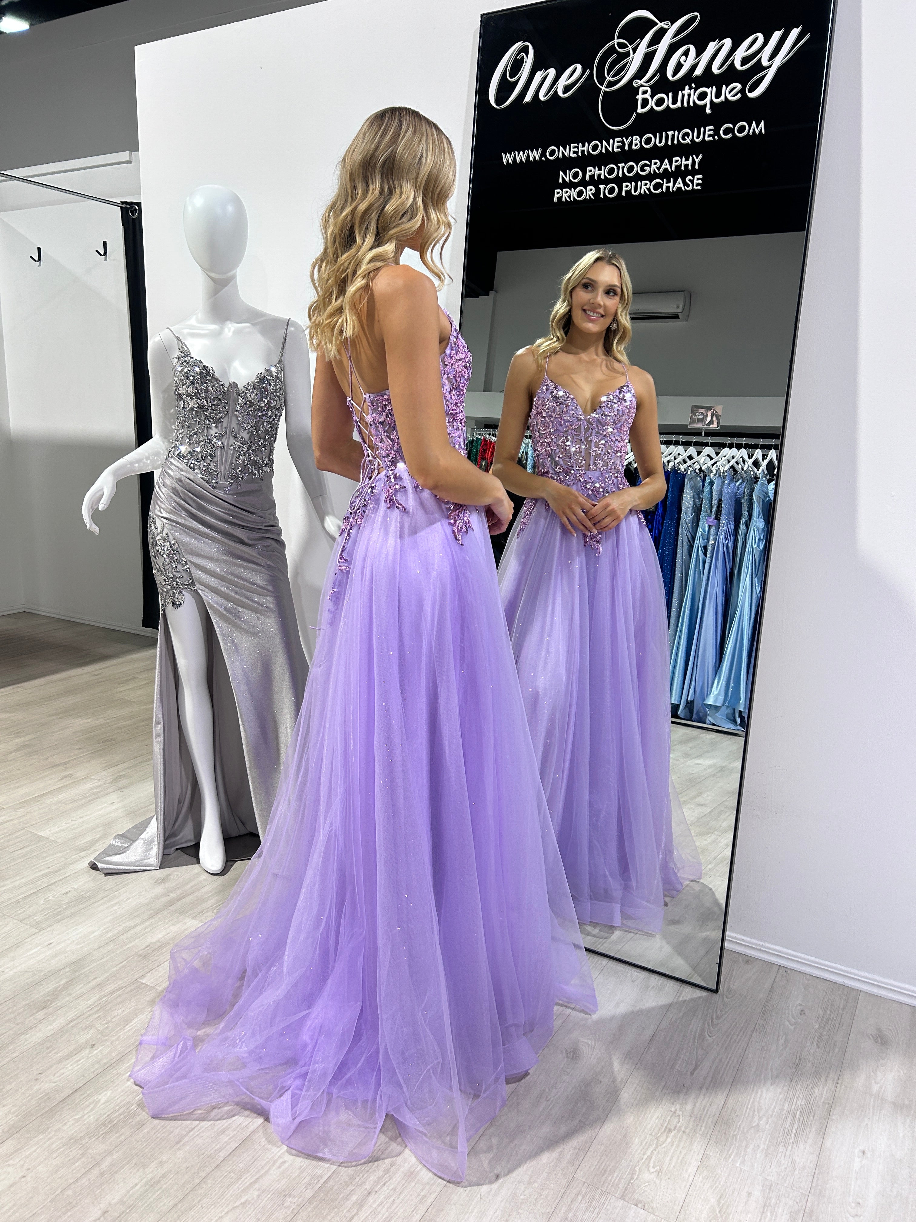 Woman in a purple Honey Couture NOVINE Sequin & Glitter Mesh Tulle Formal Dress admiring herself in a mirror at an Australian formal store.