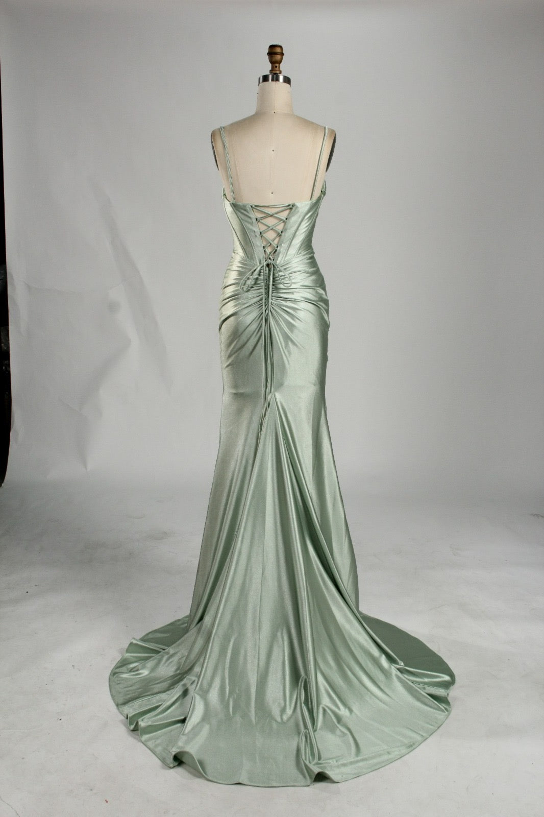 Back view of sage satin mermaid dress with lace-up corset detail and train, perfect for formal occasions.