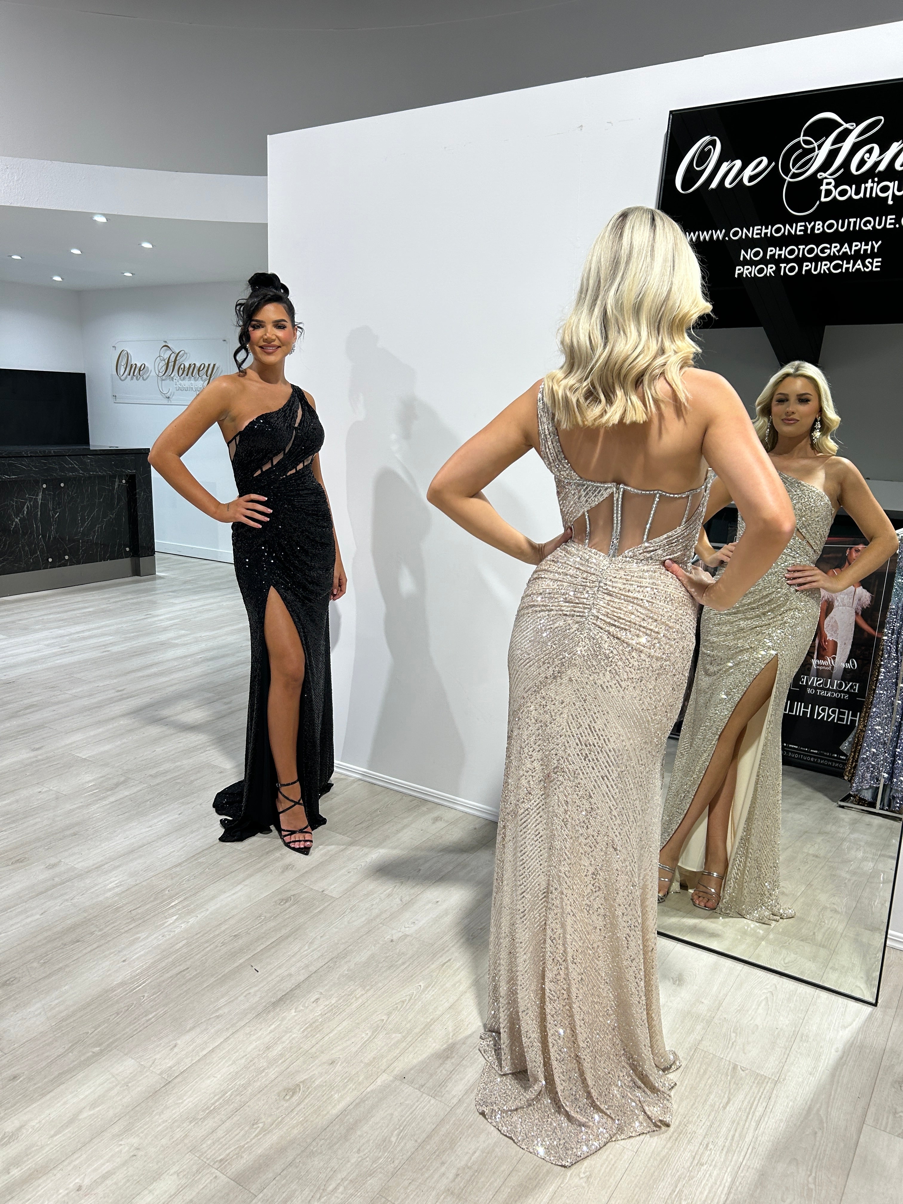 Honey Couture IRIS black one shoulder sequin dress displayed in boutique, featuring ruched design, perfect for prom or evening event.