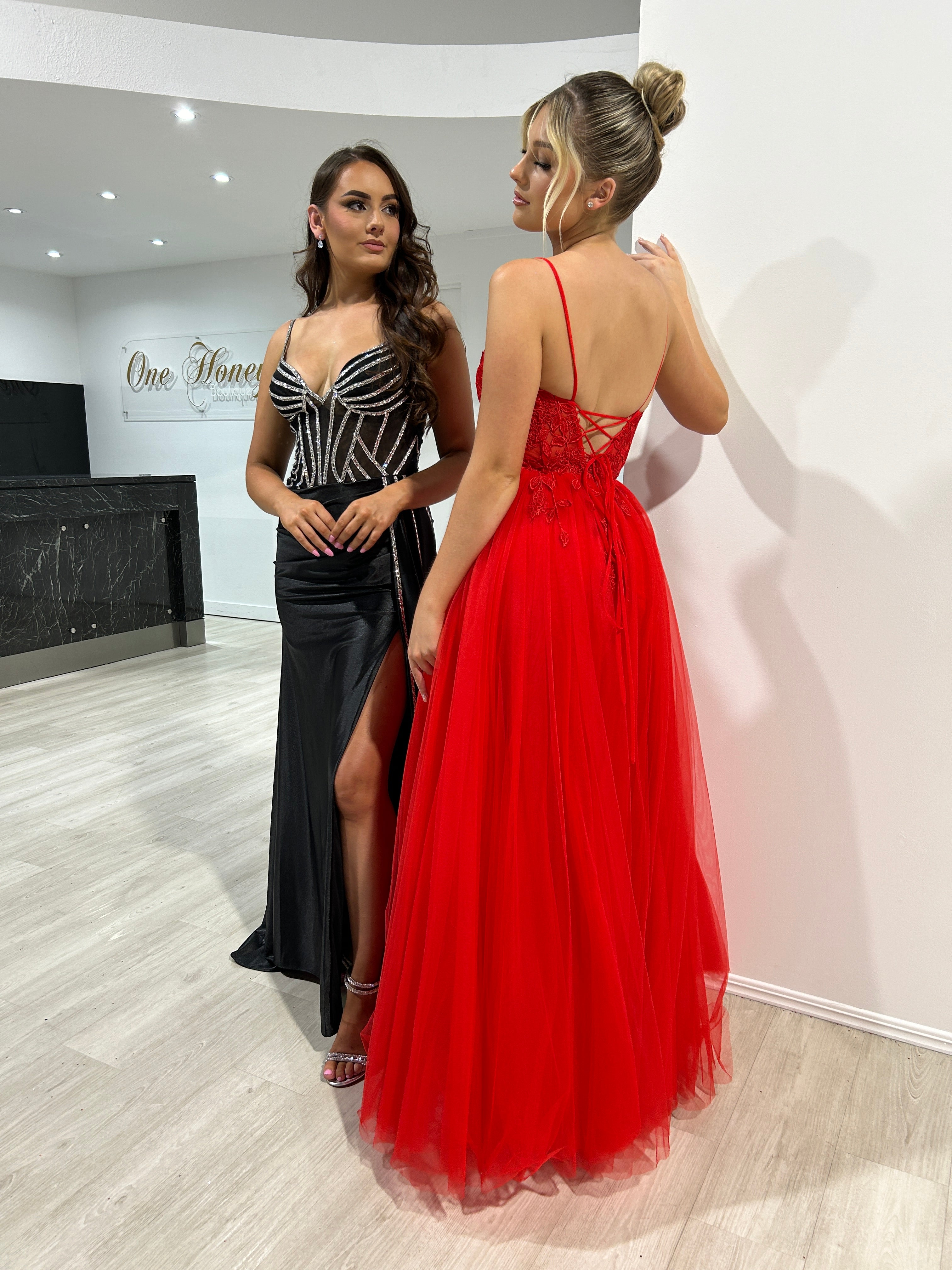 Two women in elegant gowns, featuring a Honey Couture JARRISSA Red Tulle A-Line Formal Dress with corset back, in a stylish setting.