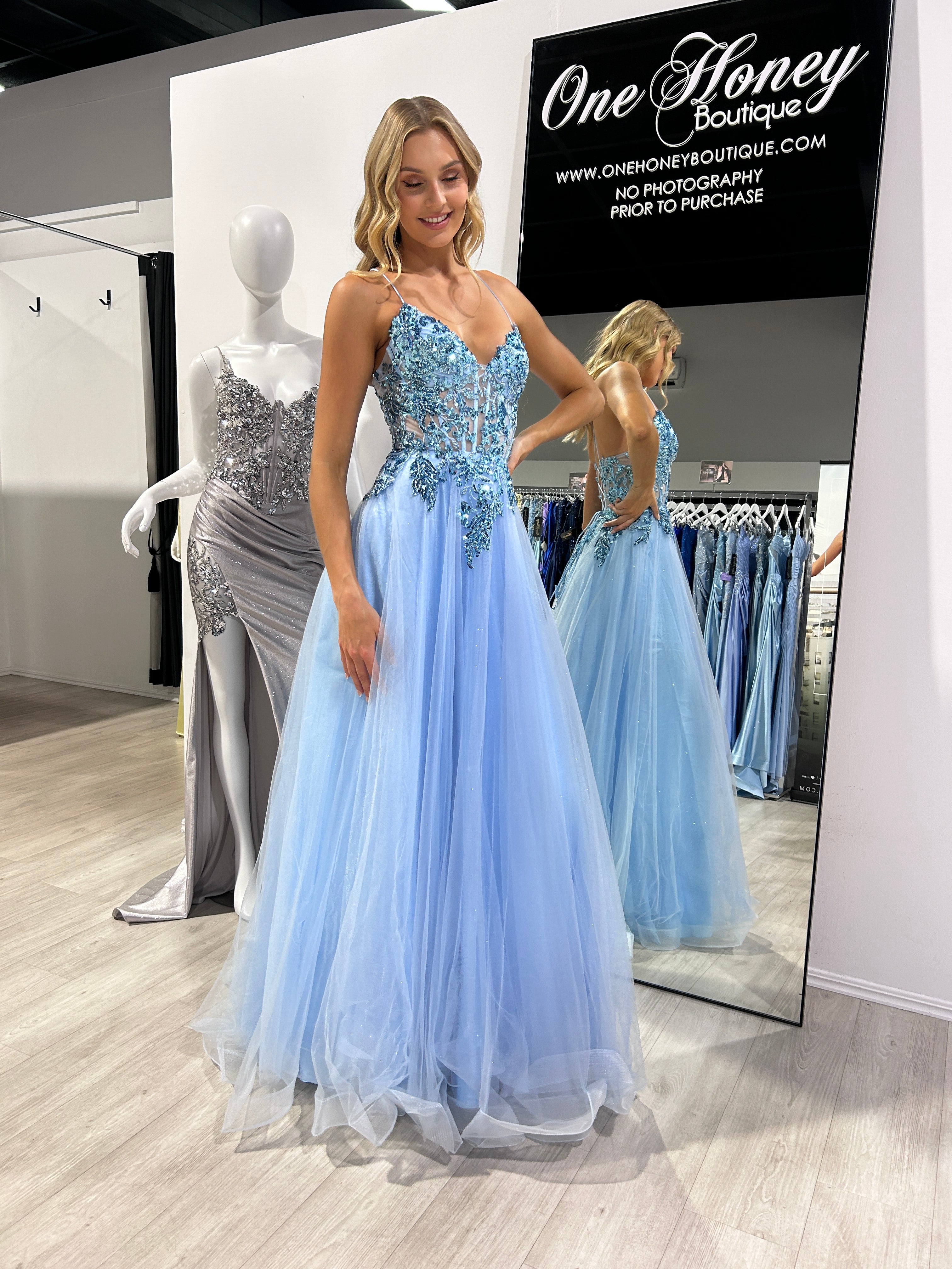 Woman wearing a blue Honey Couture NOVINE sequin & glitter mesh formal prom dress in a boutique setting. Designer prom dress, Australian formal store.