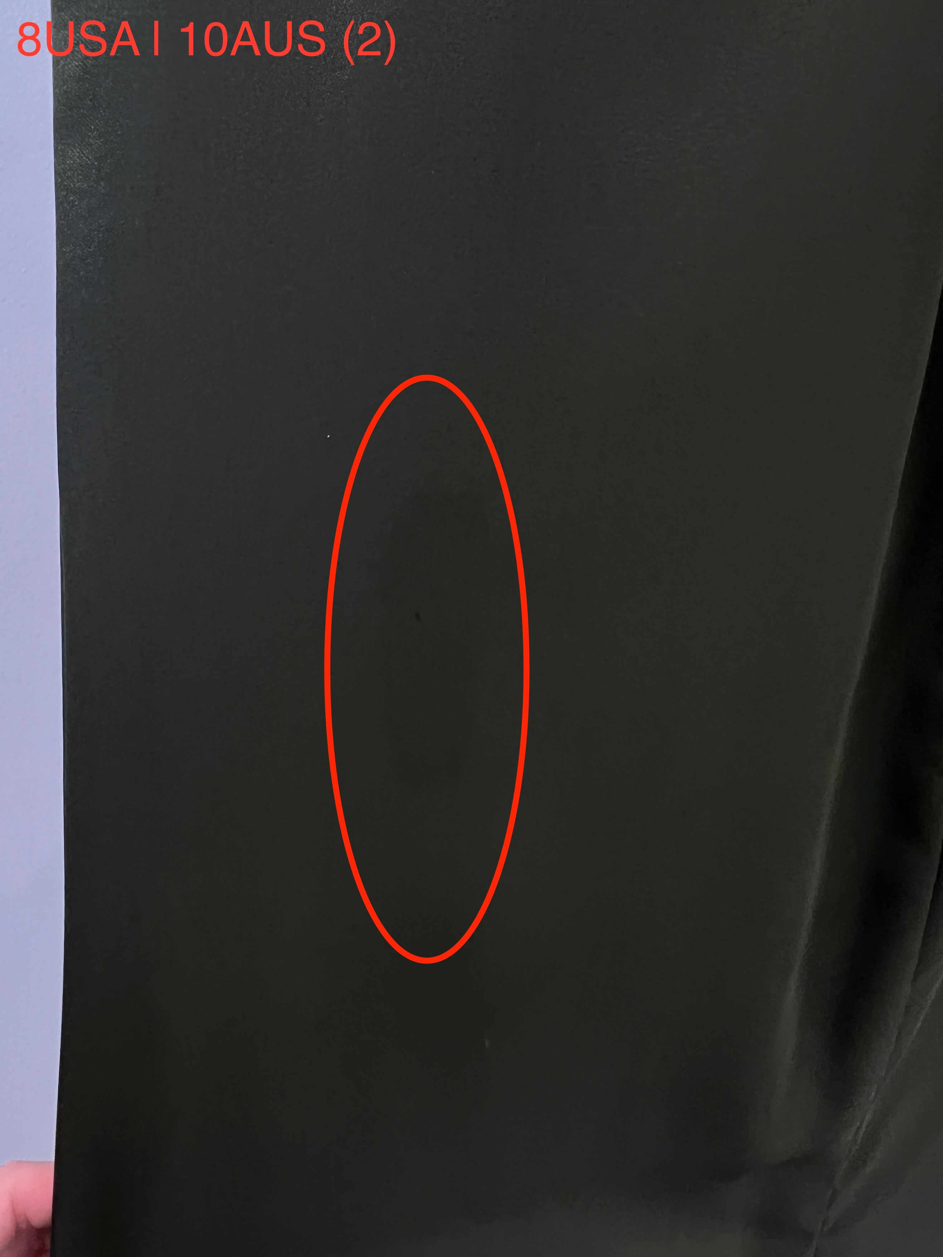 Close-up of the Honey Couture ZENDAYA olive green satin fabric with a circled area showing a detail, showcasing the gown's luxurious material.