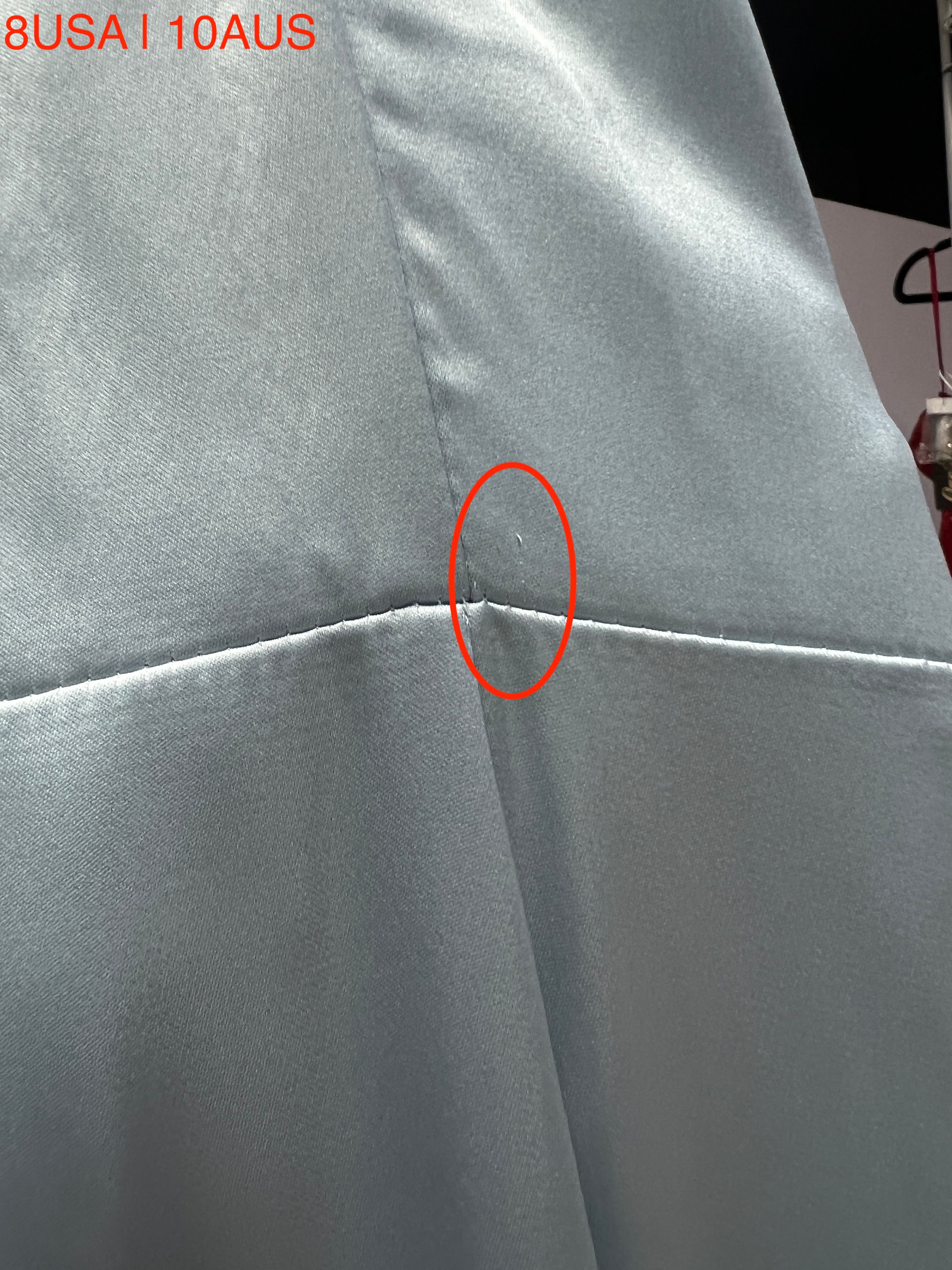 Close-up of a light blue satin fabric from a Honey Couture ZENDAYA dress, showcasing a small flaw marked with a red circle. Size 8USA 10AUS.