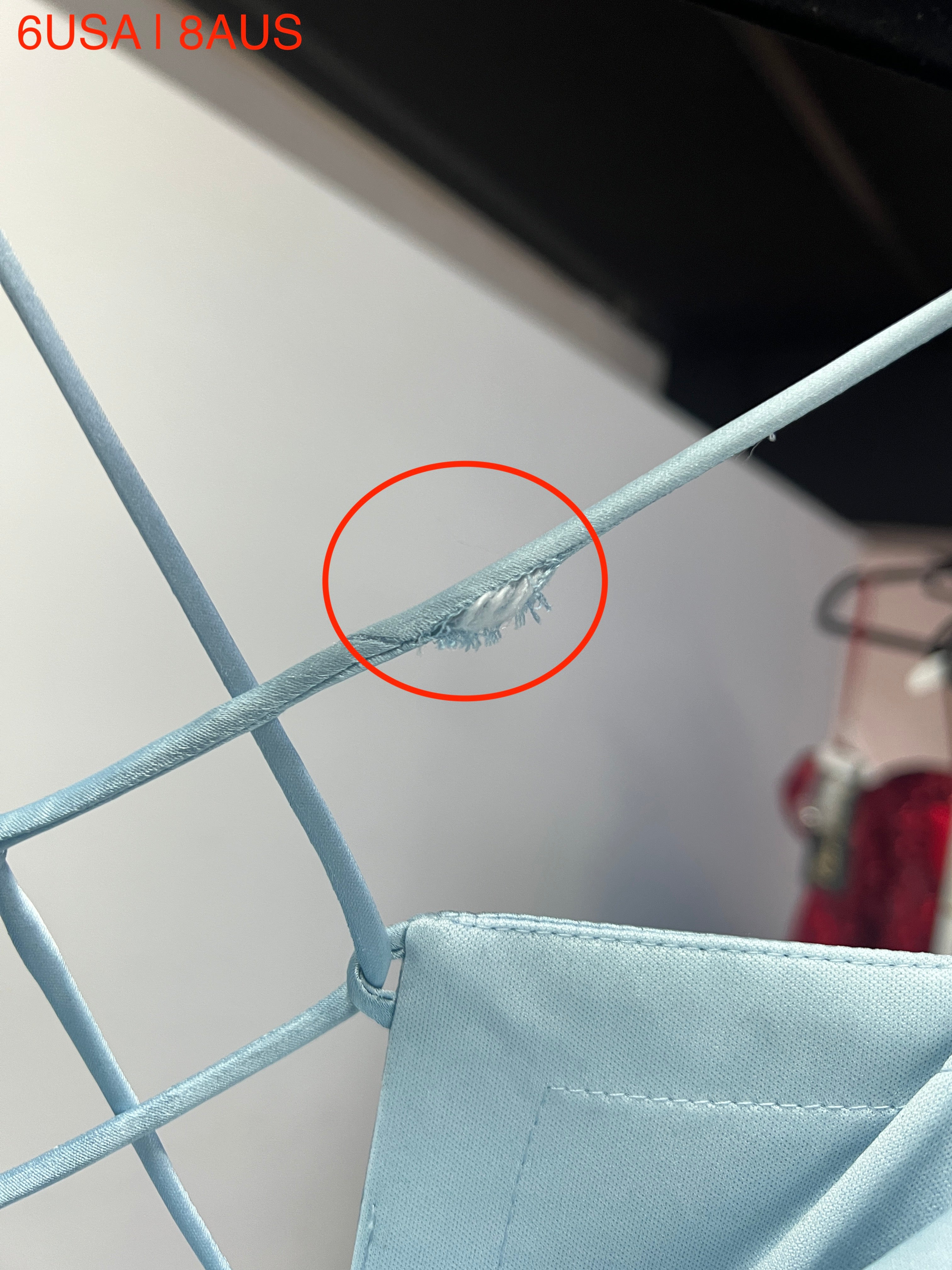 Close-up view of the Honey Couture ZENDAYA dress in light blue satin showing minor fabric fray near the strap.