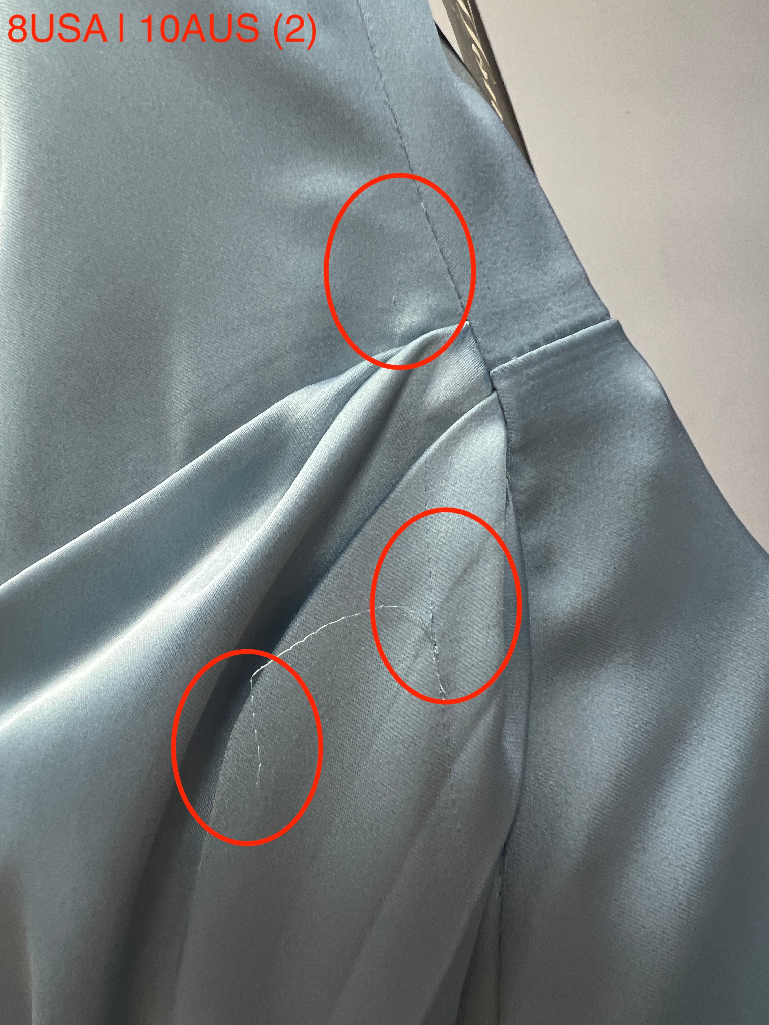 Close-up of blue satin fabric with stitching details and size indicator, showing small imperfections, from Honey Couture ZENDAYA dress.