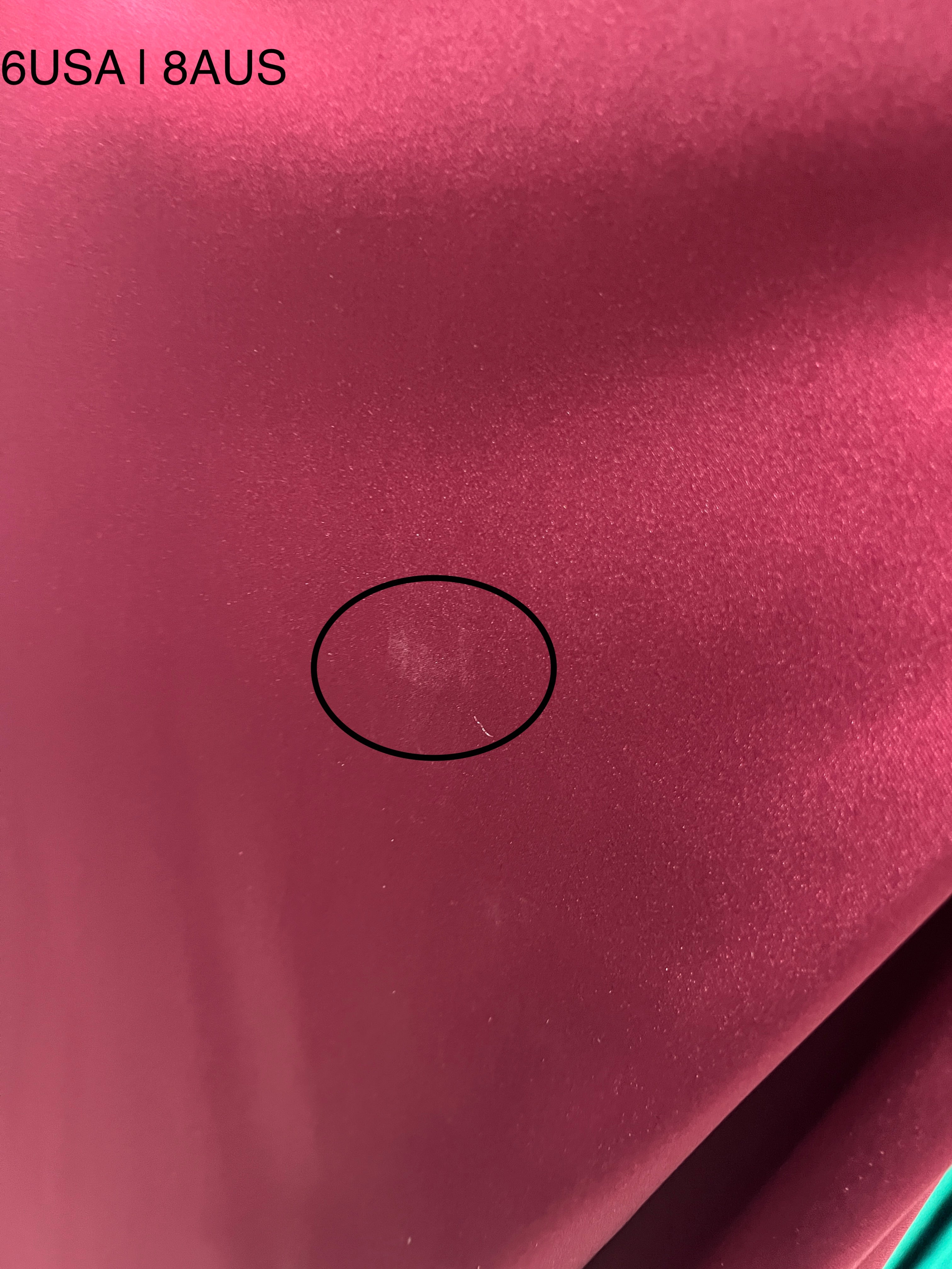 Close-up of Honey Couture burgundy satin fabric with minor flaw, size 6USA/8AUS marked, from Australian designer evening gown collection.