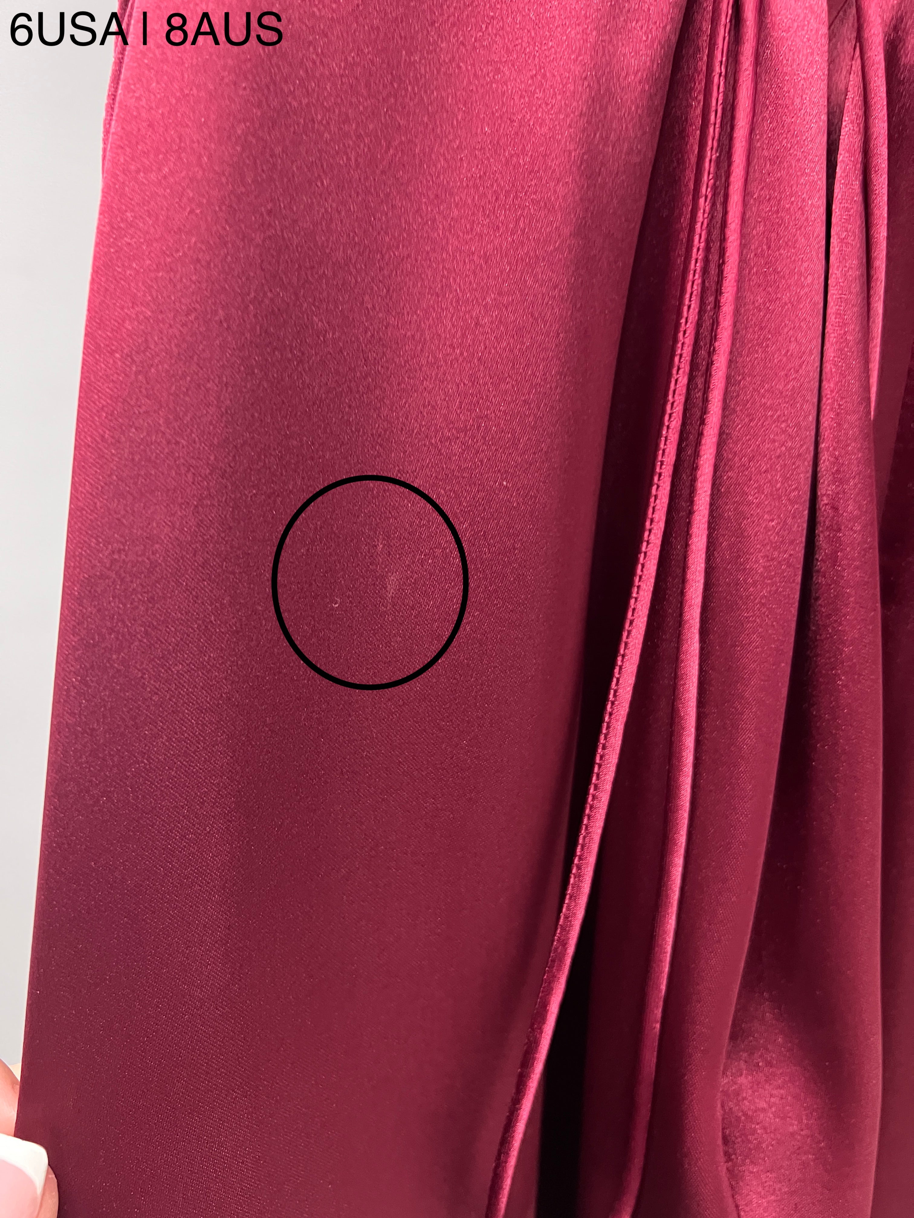 Close-up of Honey Couture ZENDAYA Burgundy Satin Dress fabric with minor flaw circled, showcasing the Australian Designer's work.