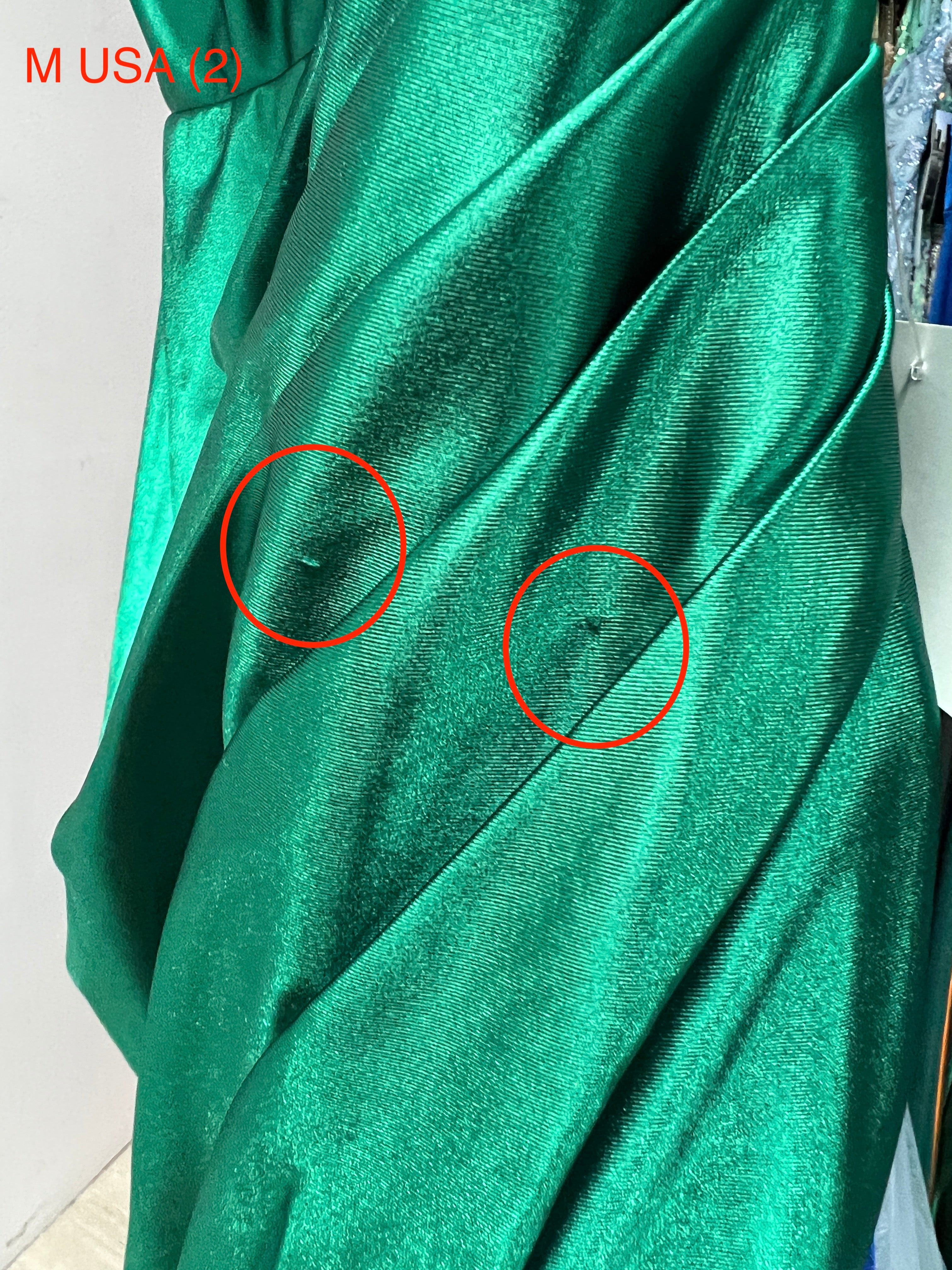 Close-up of the Honey Couture SHARYN Emerald Green evening gown showing fabric details and sheen, with minor imperfections highlighted.