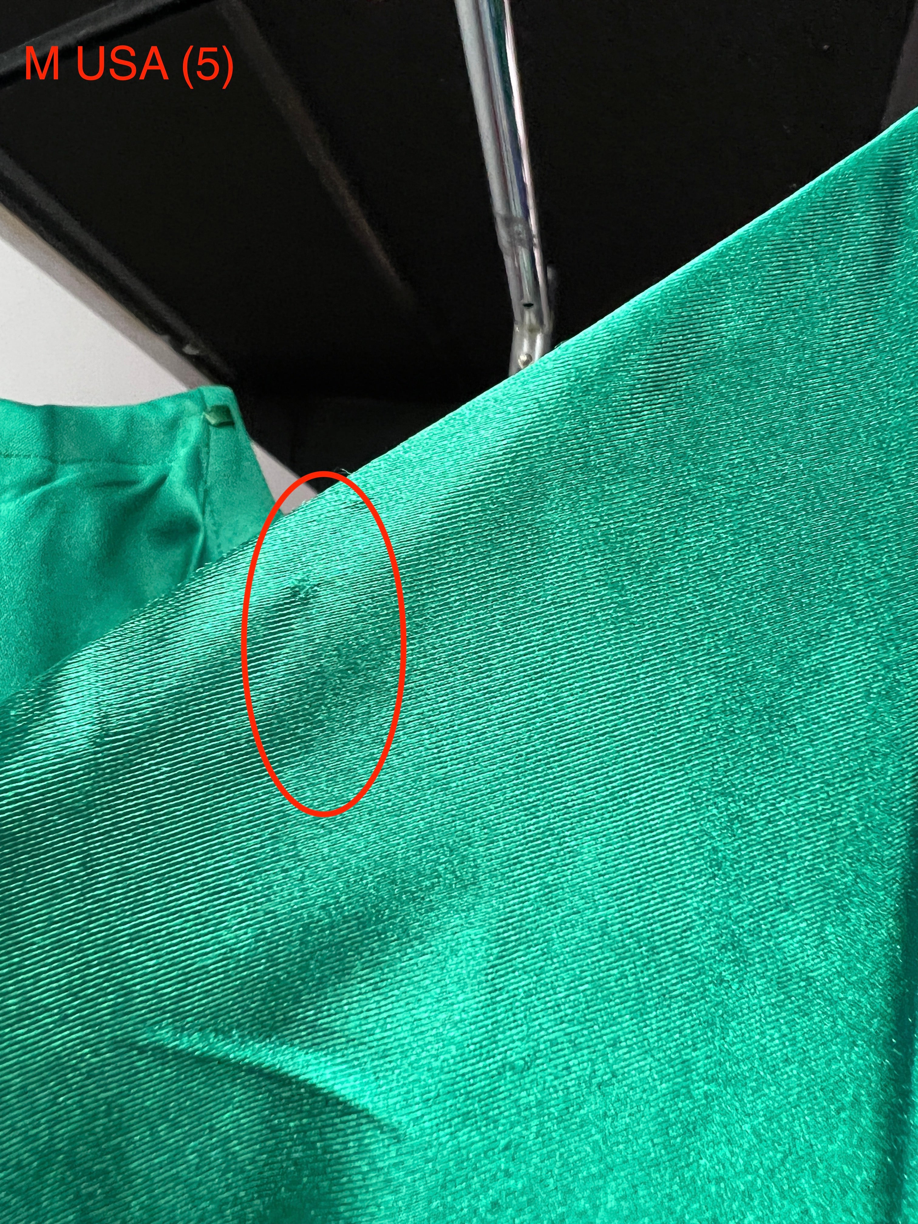 Close-up of Honey Couture SHARYN emerald green dress fabric detail with minor flaw.