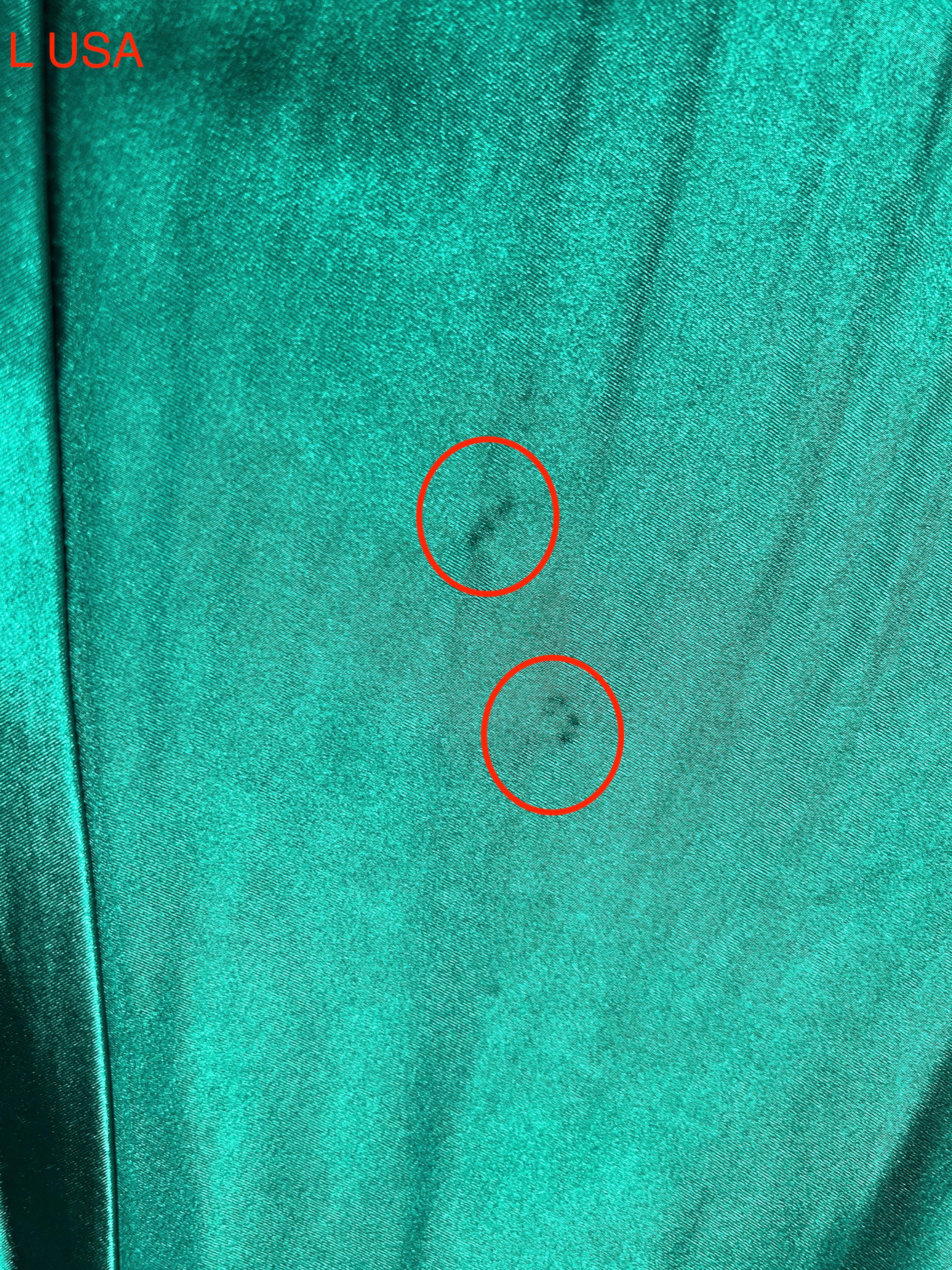 Close-up of emerald green fabric detailing on a Honey Couture dress with subtle markings highlighted.
