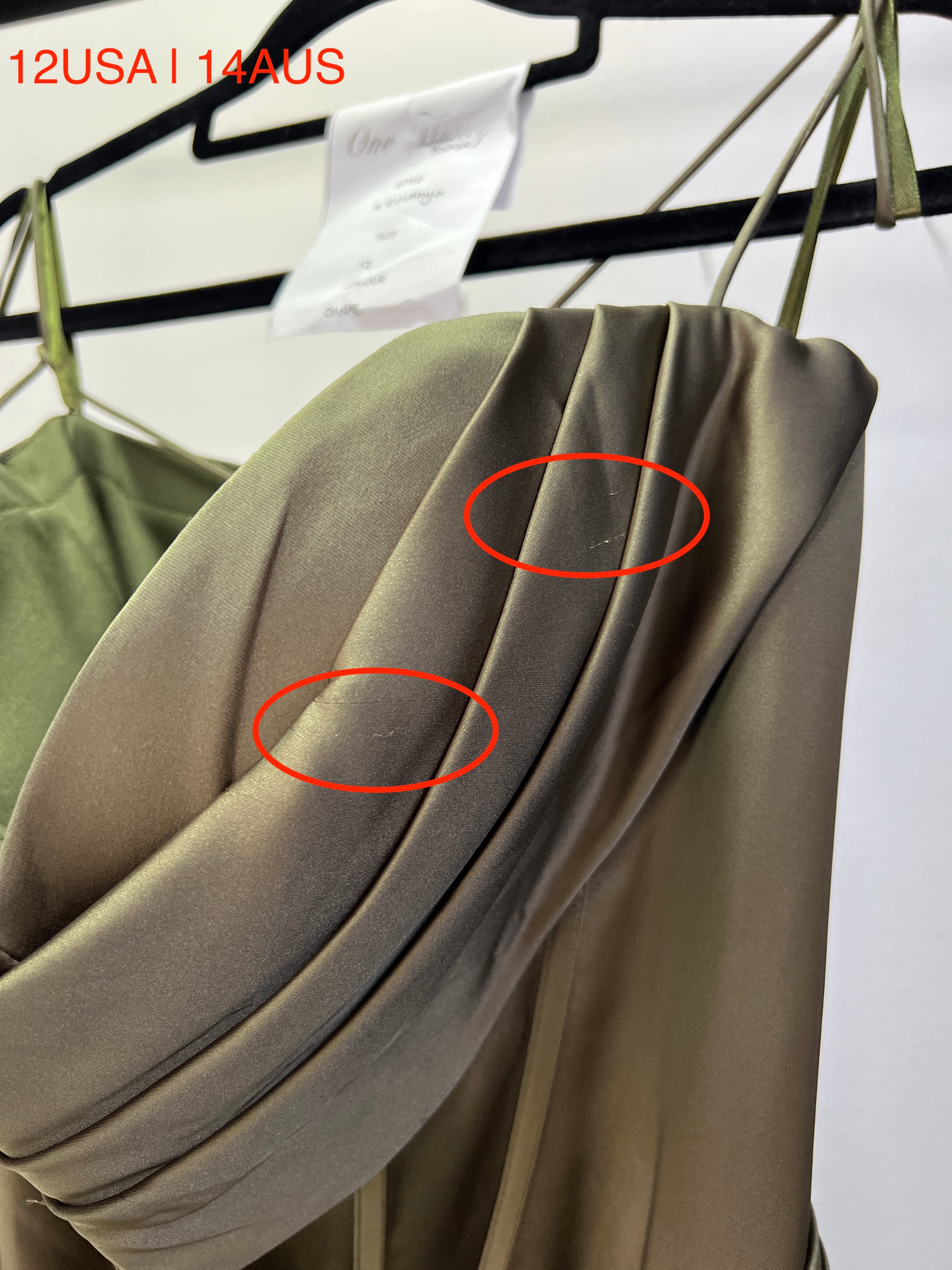 Close-up of Honey Couture ZENDAYA olive green satin corset bustier dress with visible fabric imperfection marked by red circles.