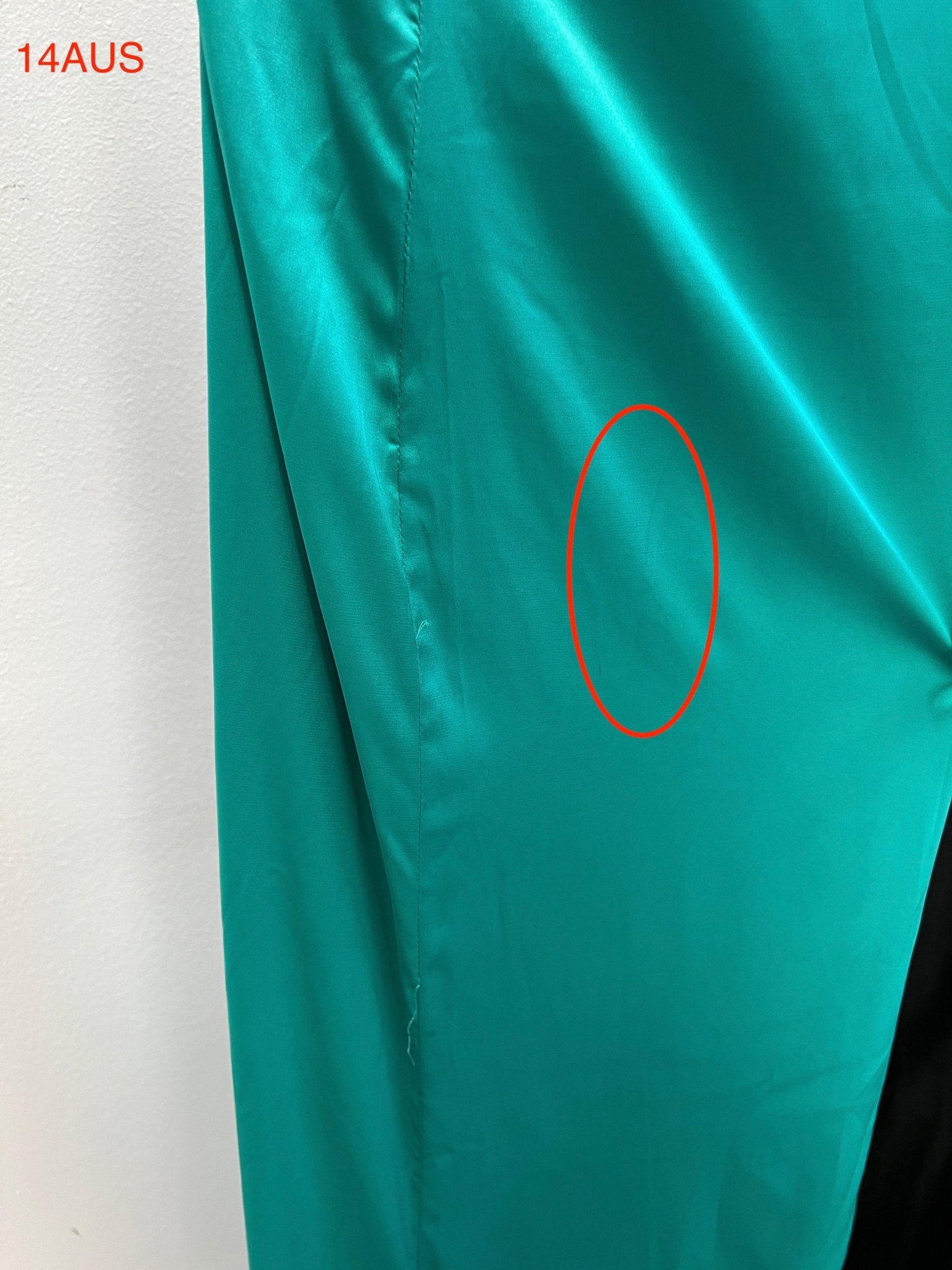 Close-up of turquoise dress fabric showing texture, with size 14AUS marking. Highlighted area on Australian designer dress.