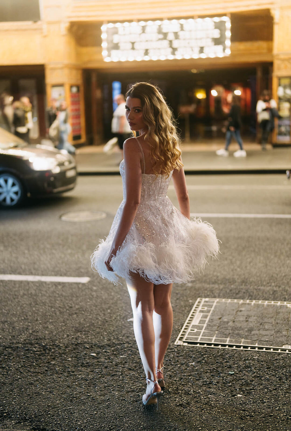 Woman in Monroe white bustier corset dress with sequins and feathers, ideal for hens party or second bridal mini dress.