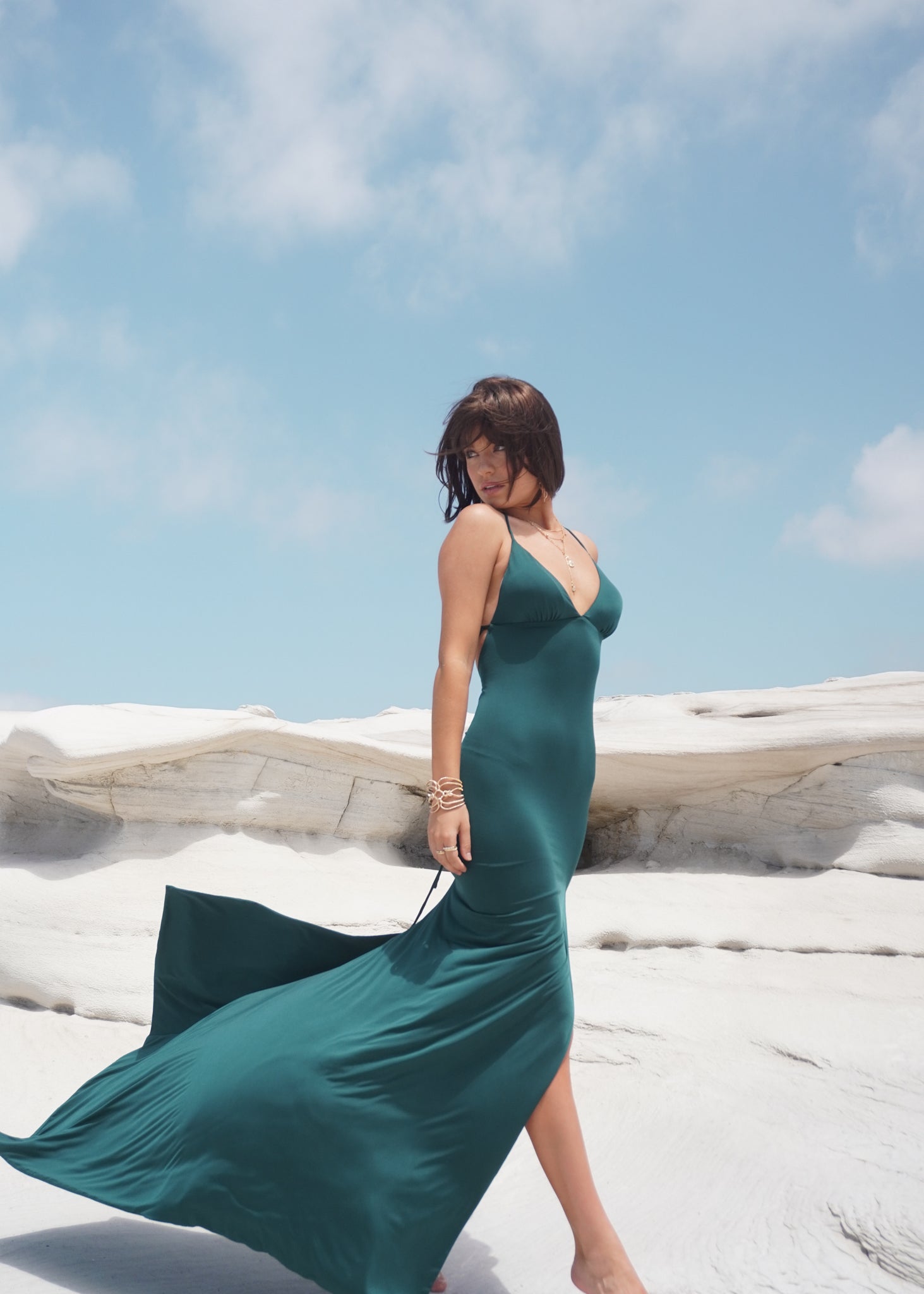 Elegant woman in teal mermaid prom dress by Australian designer, Amy Taylor. Features bodycon fit, halter straps, and leg split.