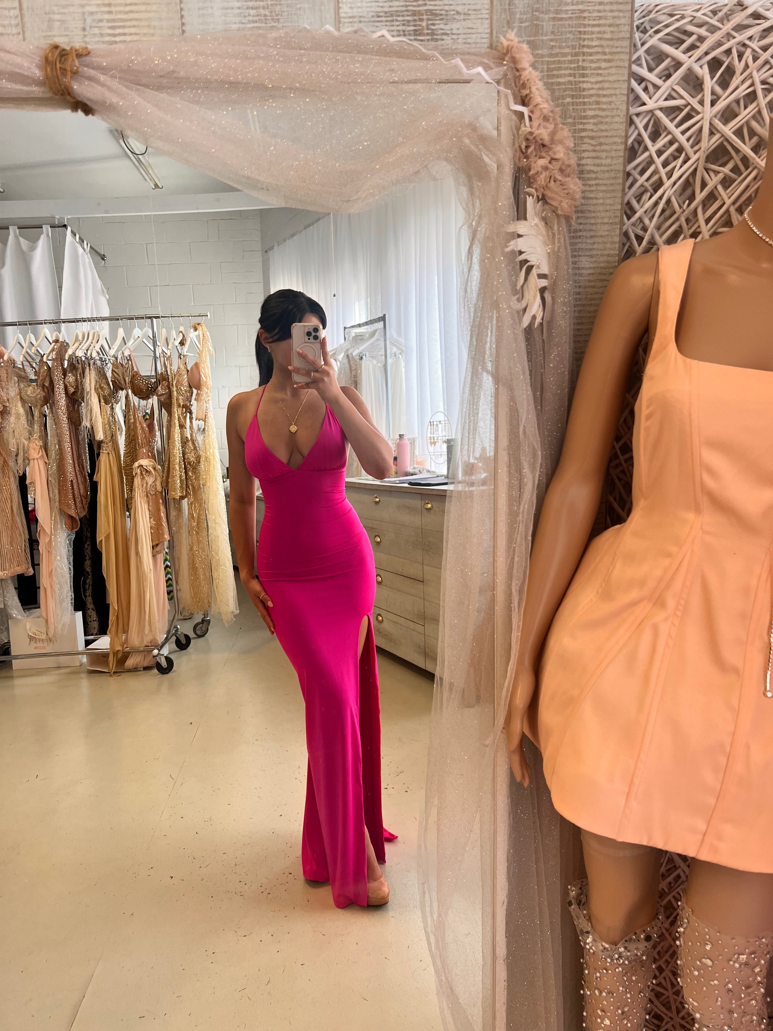 Elegant one-shoulder pink bodycon dress with halter neckline, side leg split, and bandage fabric showcased in boutique setting.