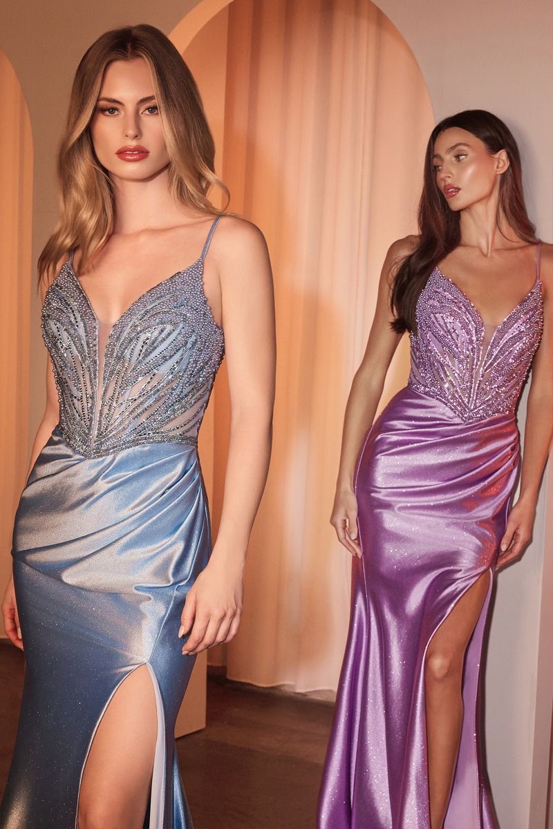 Two women wearing fitted satin gowns with intricate beaded bodices and thigh-high slits, posing in an elegant setting.