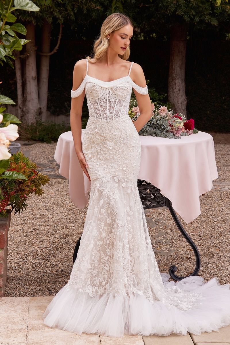 Woman wearing Divinity Bridal LADA Off Shoulder Lace Beaded affordable bridal wedding dress, fit and flare style in garden.