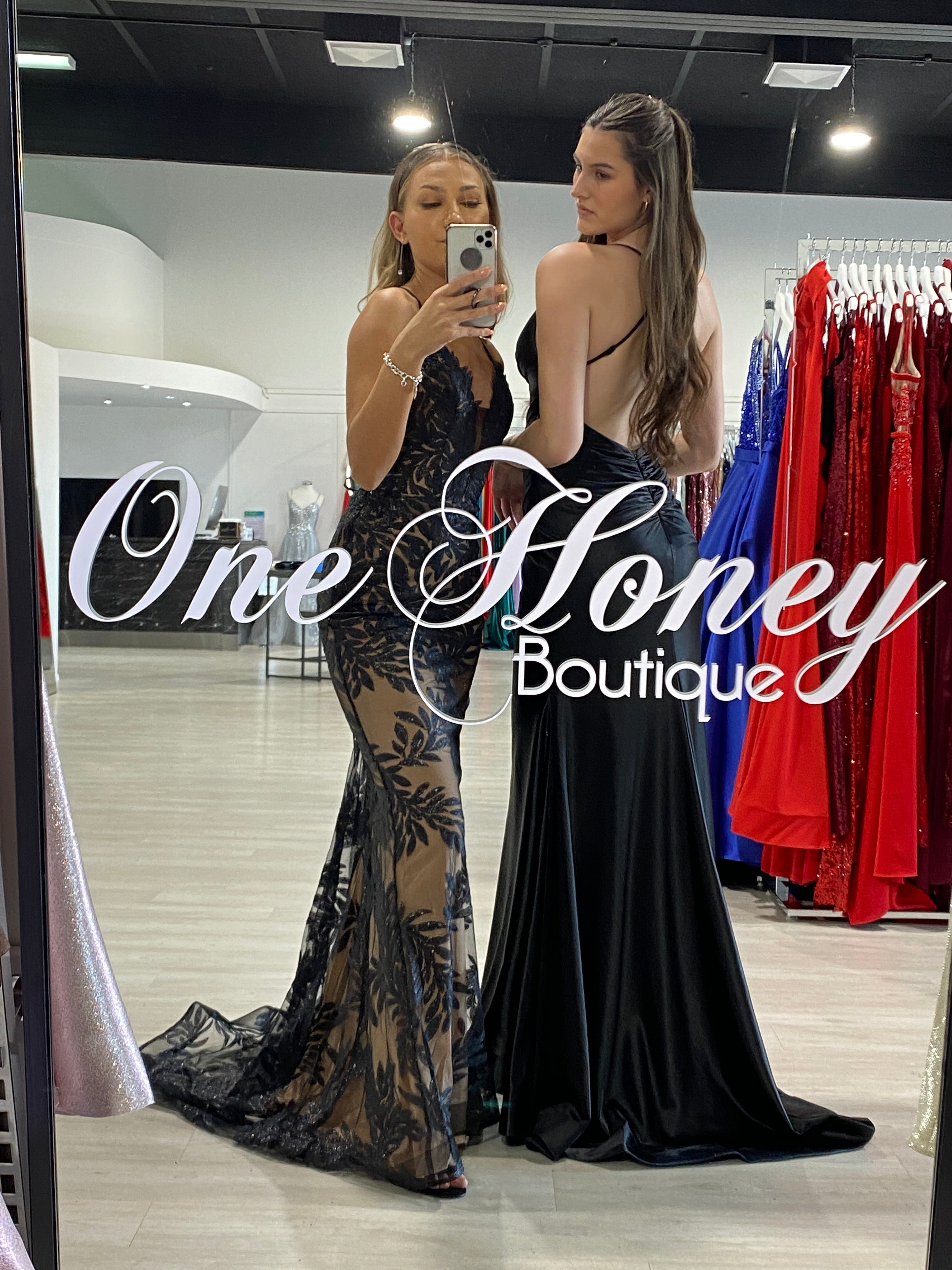 Elegant lace-patterned and satin formal gowns displayed at One Honey Boutique in store mirror, Brisbane to Gold Coast, Australia.