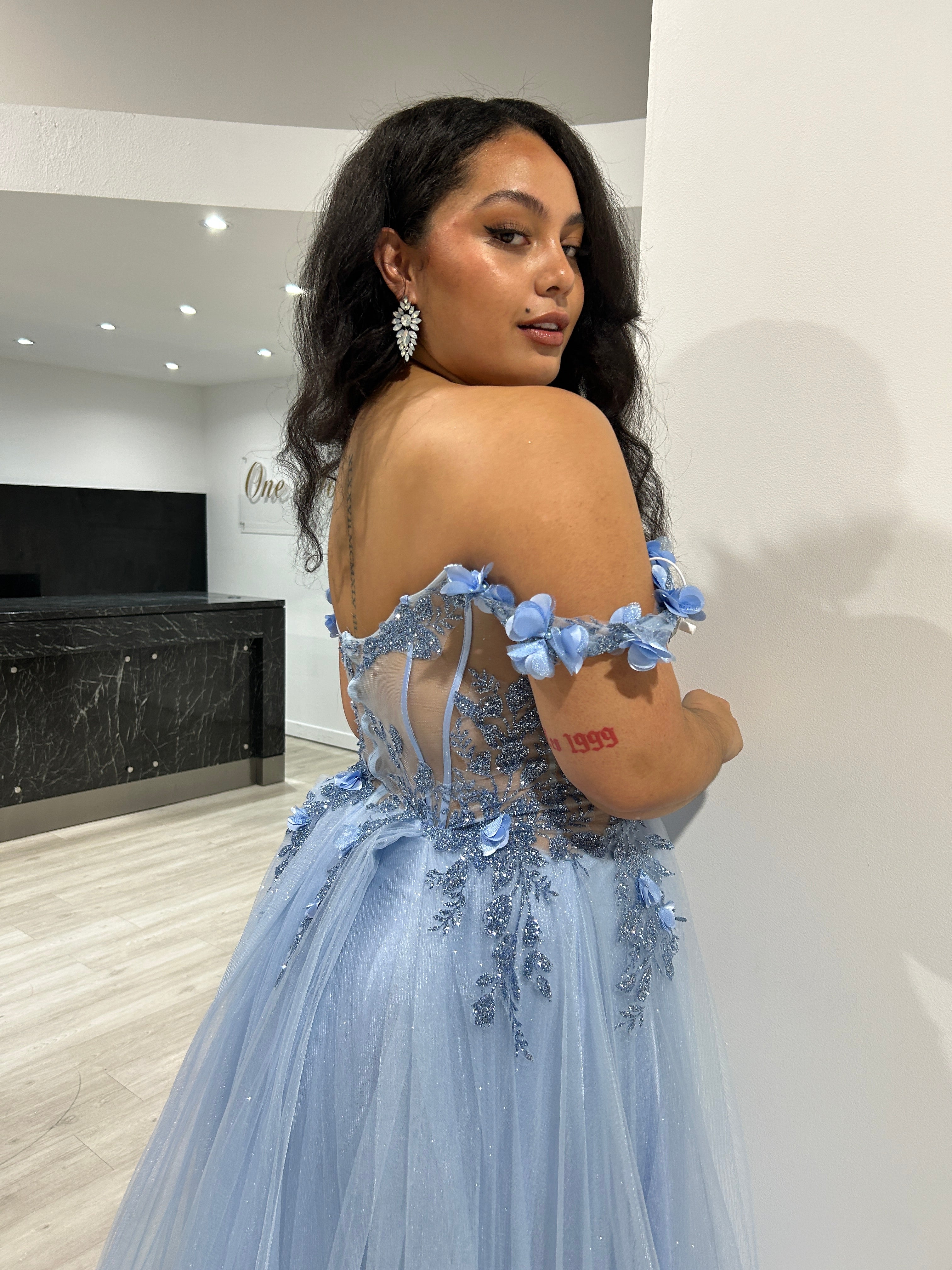 Model wearing Honey Couture KARRISA blue glitter off-the-shoulder formal dress by Australian designer. Perfect prom or evening gown look.