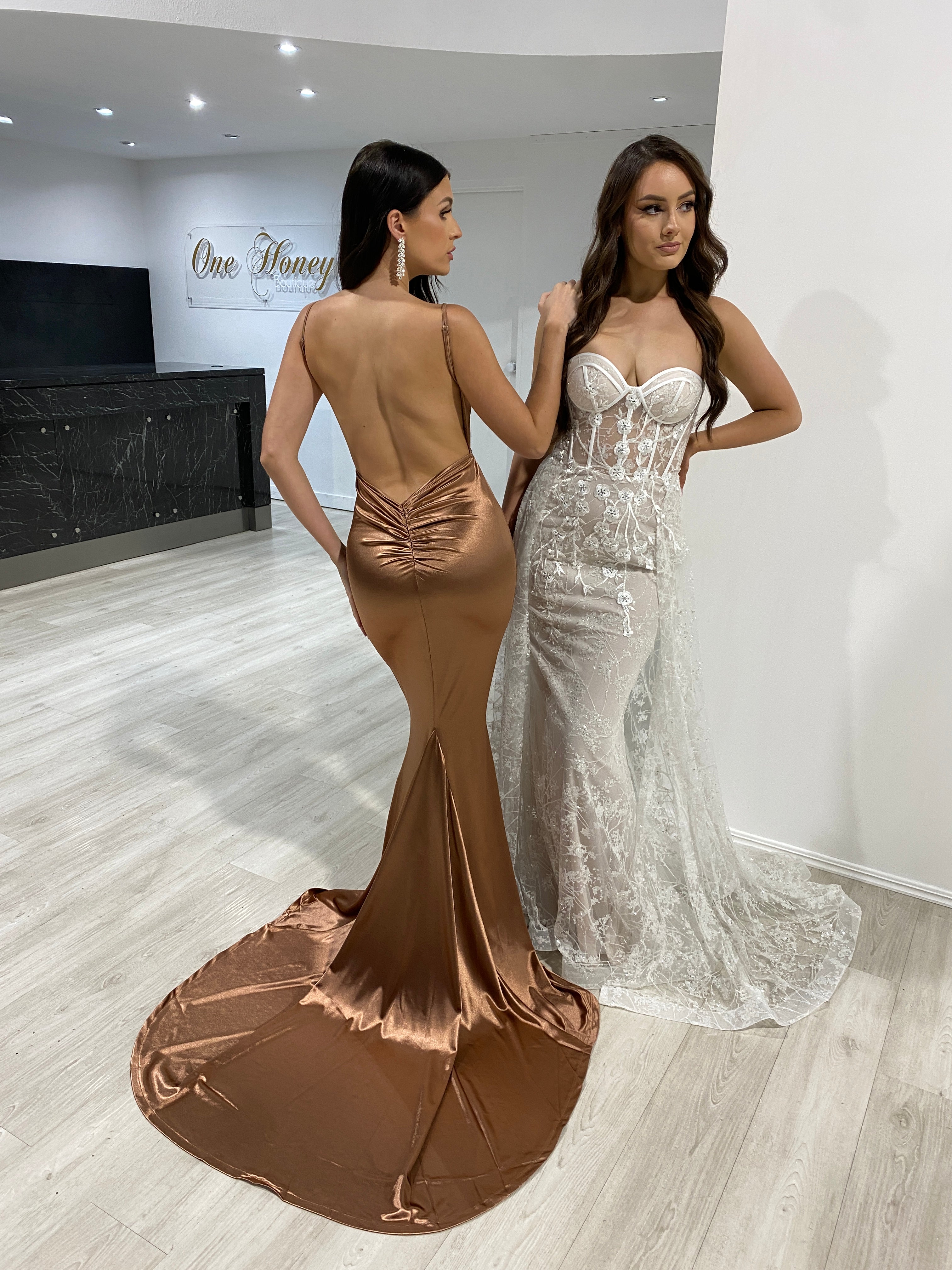 Two women in Honey Couture evening gowns, one in MILEE Low Back bronze mermaid dress, highlighting Australian designer prom style elegance.