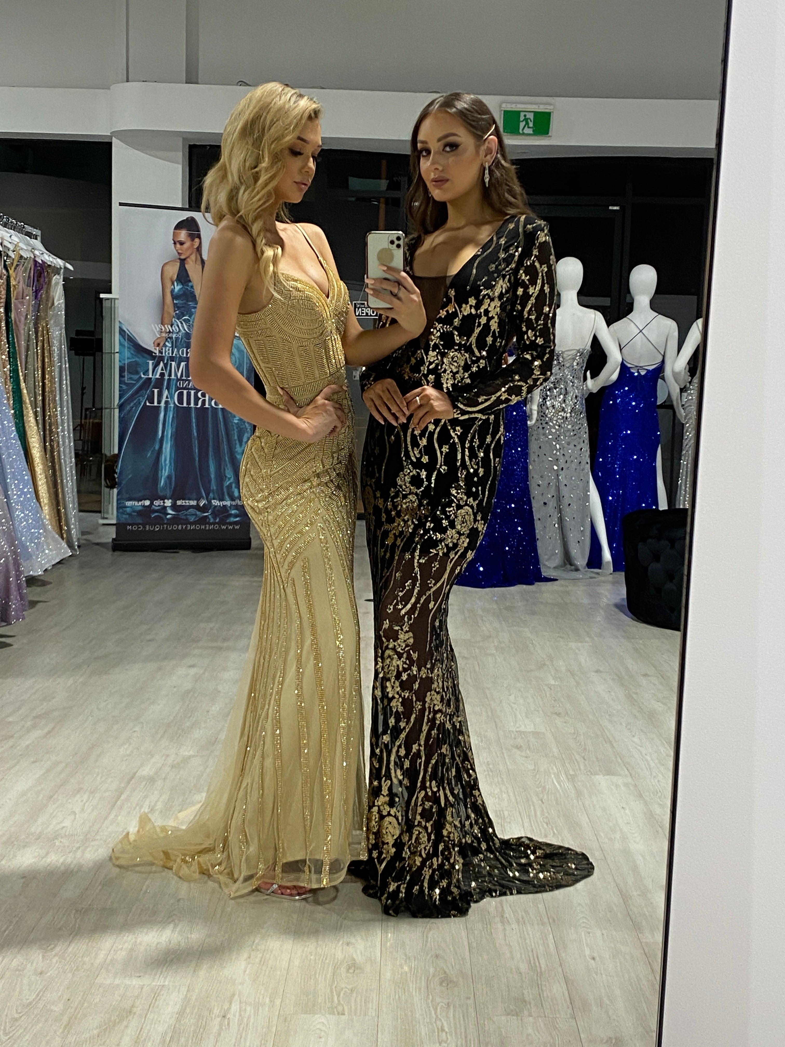 Two women wearing elegant sequin evening gowns in a fashion boutique, showcasing the Honey Couture DIAMONDS Sequin Mermaid Dress.