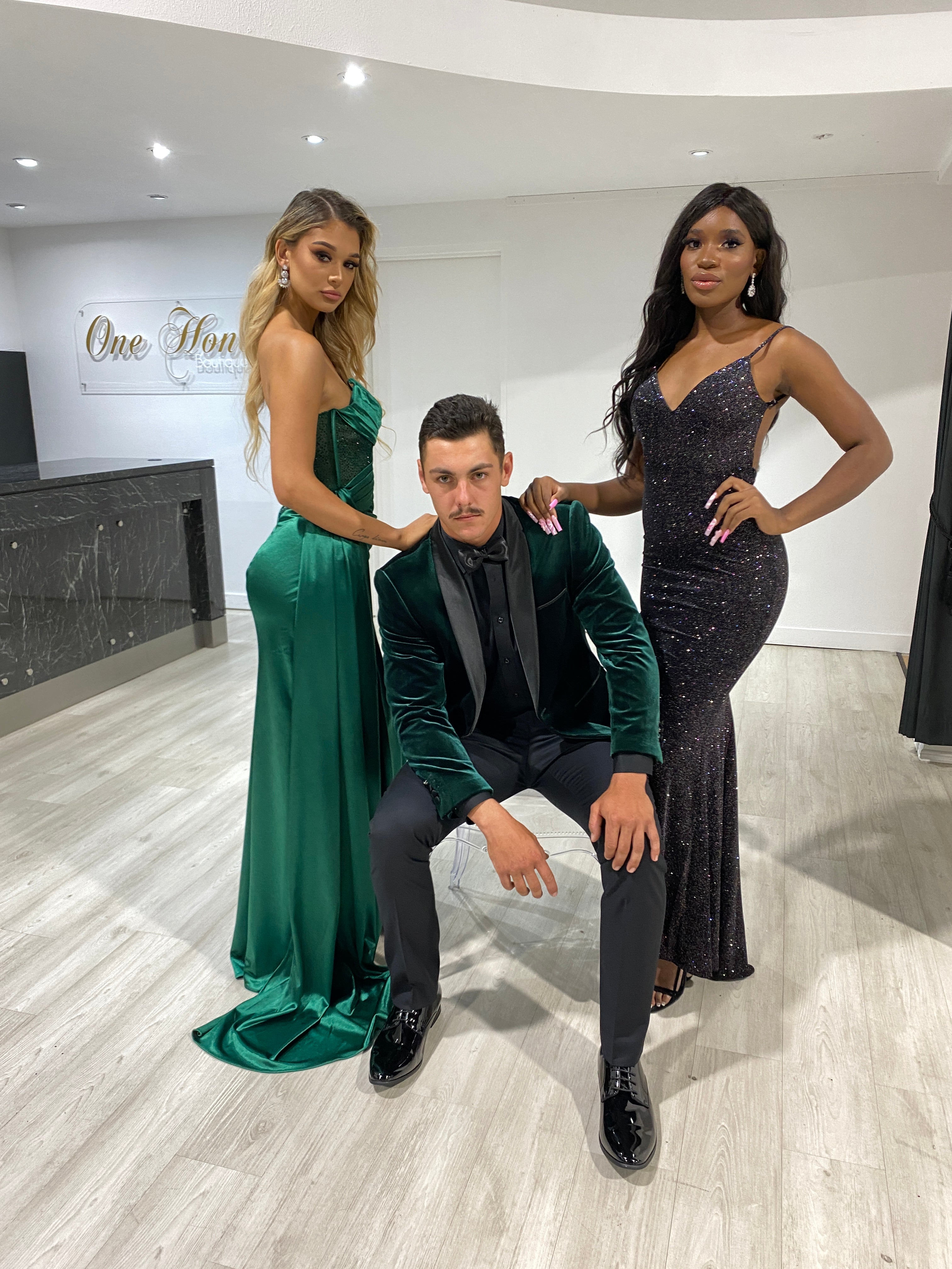 Elegant group in formal wear: man in green velvet jacket with women in emerald and black gowns. Formal attire fashion. Brisbane to Gold Coast.