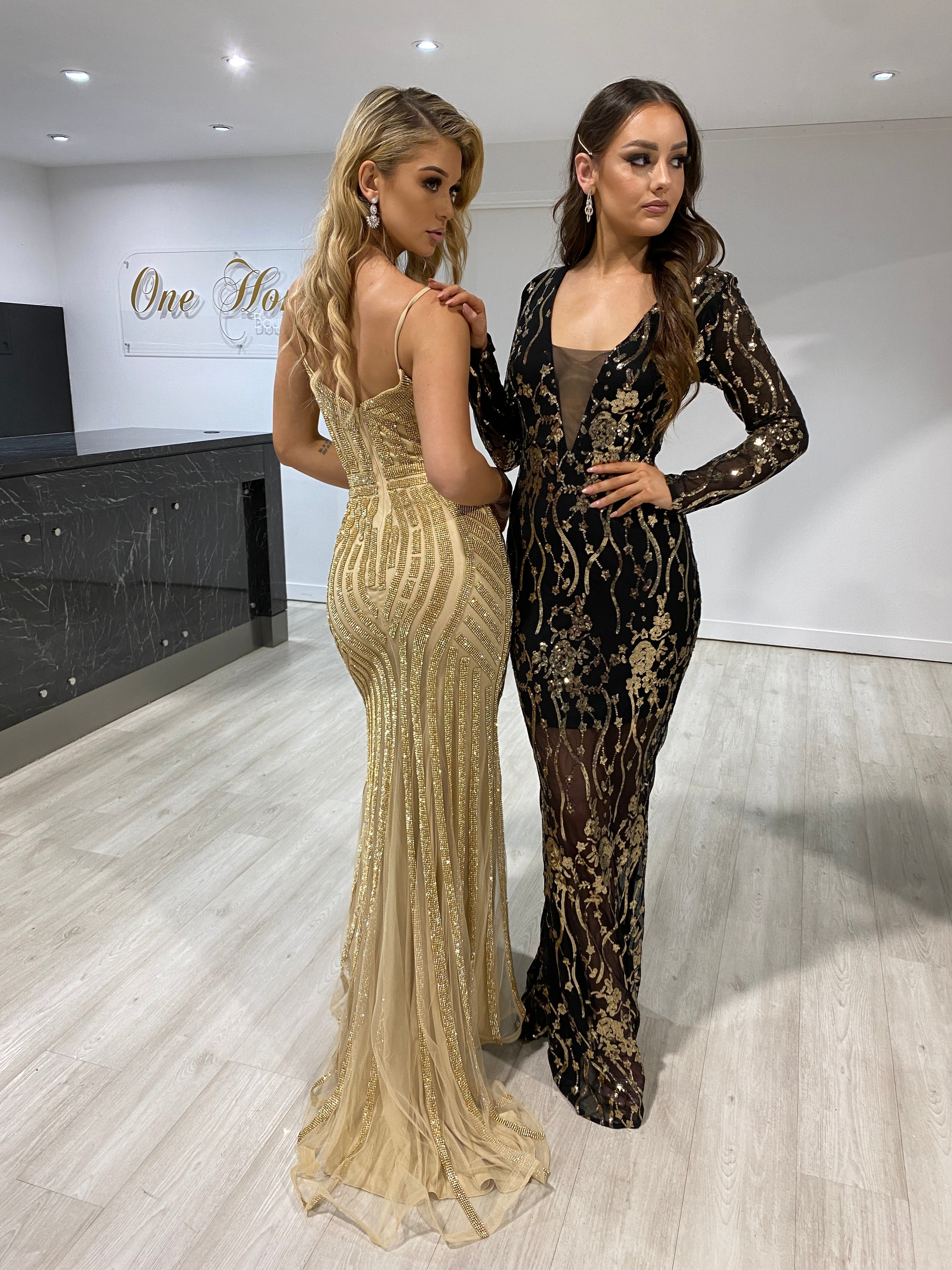 Two women in sequined evening gowns; one in a Honey Couture DIAMONDS gold mermaid dress, ideal for formal events, by an Australian designer.