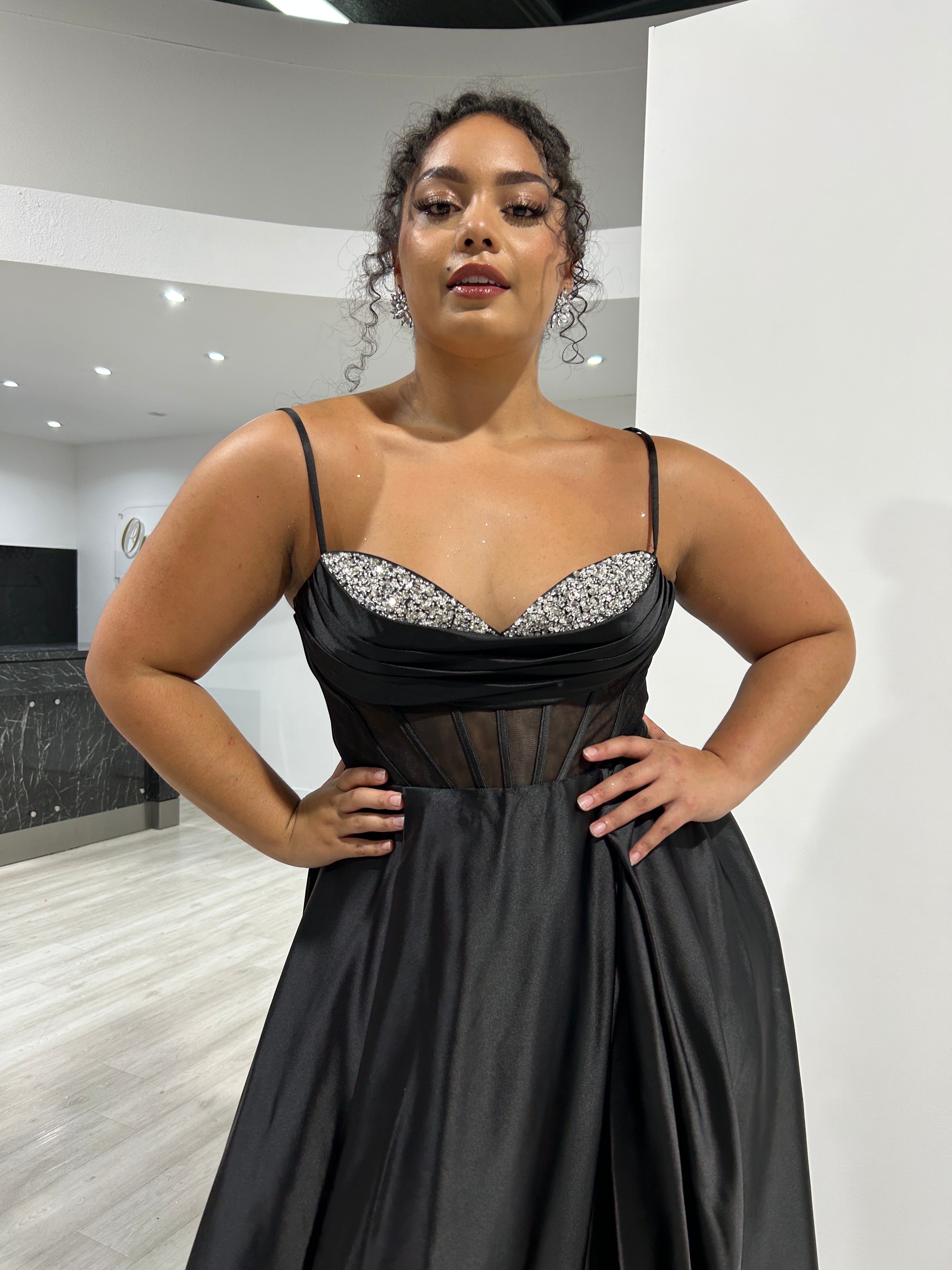 Black satin evening gown with diamanté bust and sheer corset, modeled by woman in boutique store. Fashion elegance Brisbane to Gold Coast.