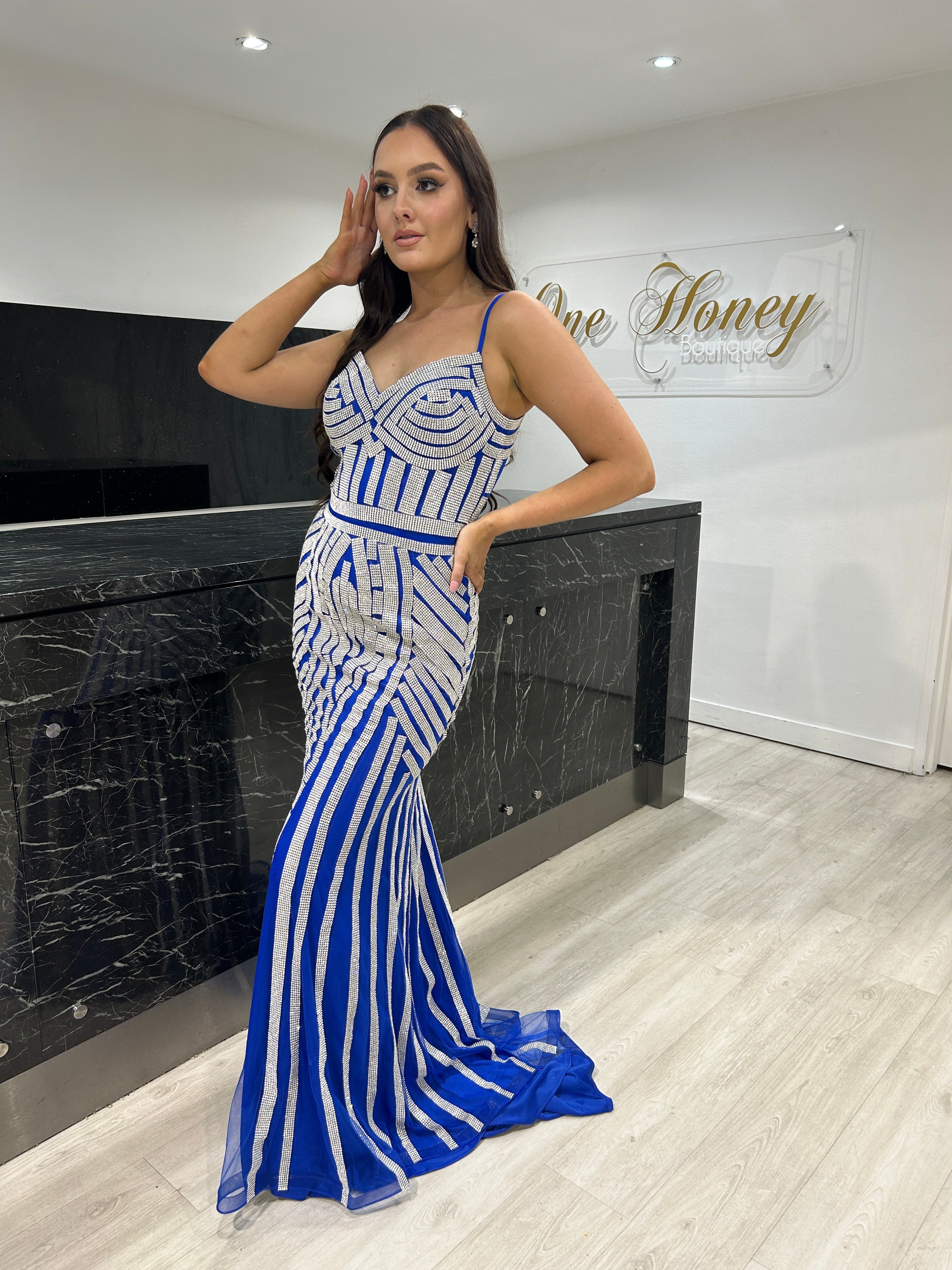 Woman wearing a blue and white striped mermaid gown in a showroom.