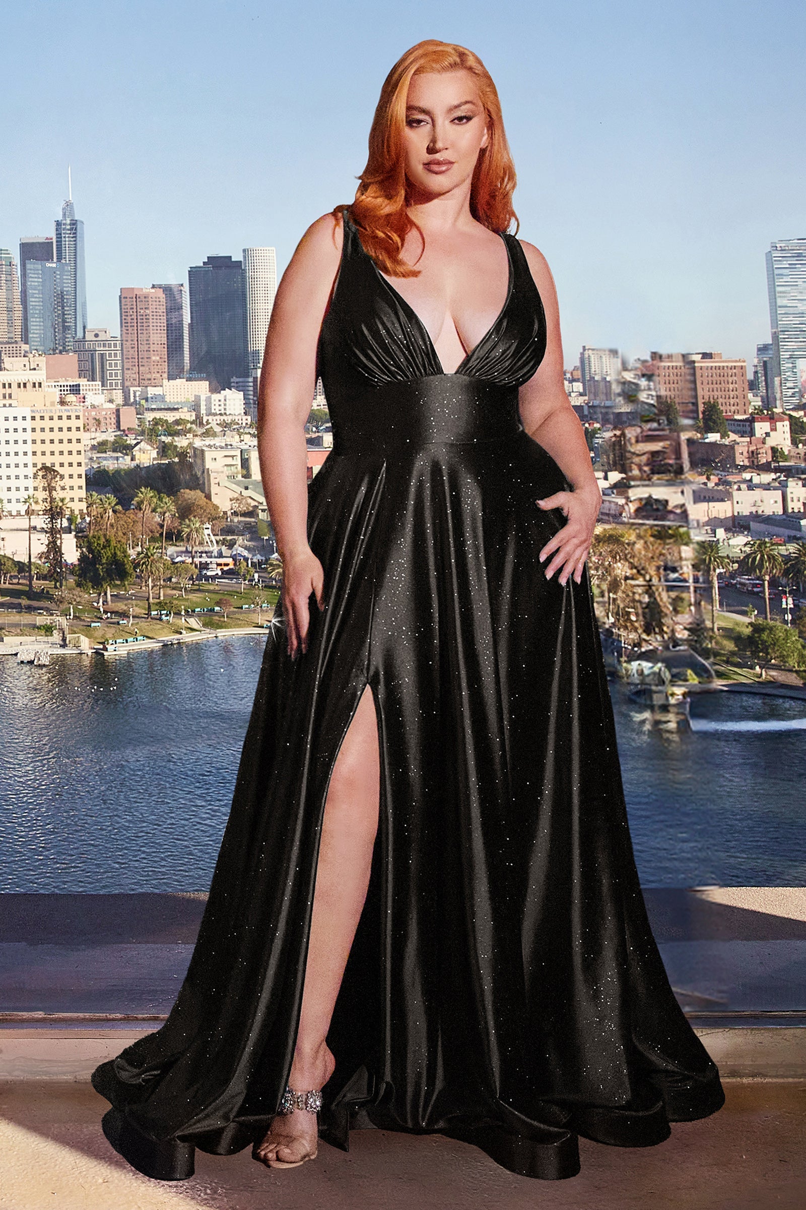 Plus size woman in a black V-neck A-line shimmer glitter prom dress with side slit, posing elegantly with city skyline backdrop.