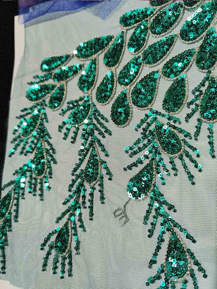 Green sequin beaded pattern on tulle fabric, elegant and intricate design for formal wear and fashion.