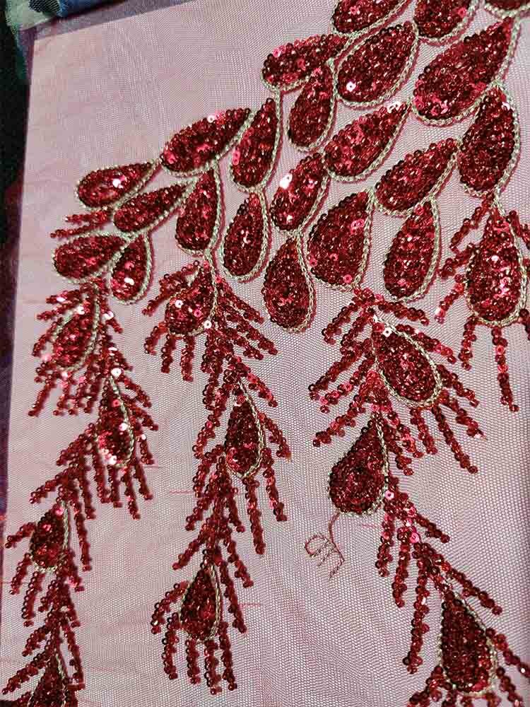 Intricate red sequin embroidery on fabric for a dazzling, luxurious appearance.