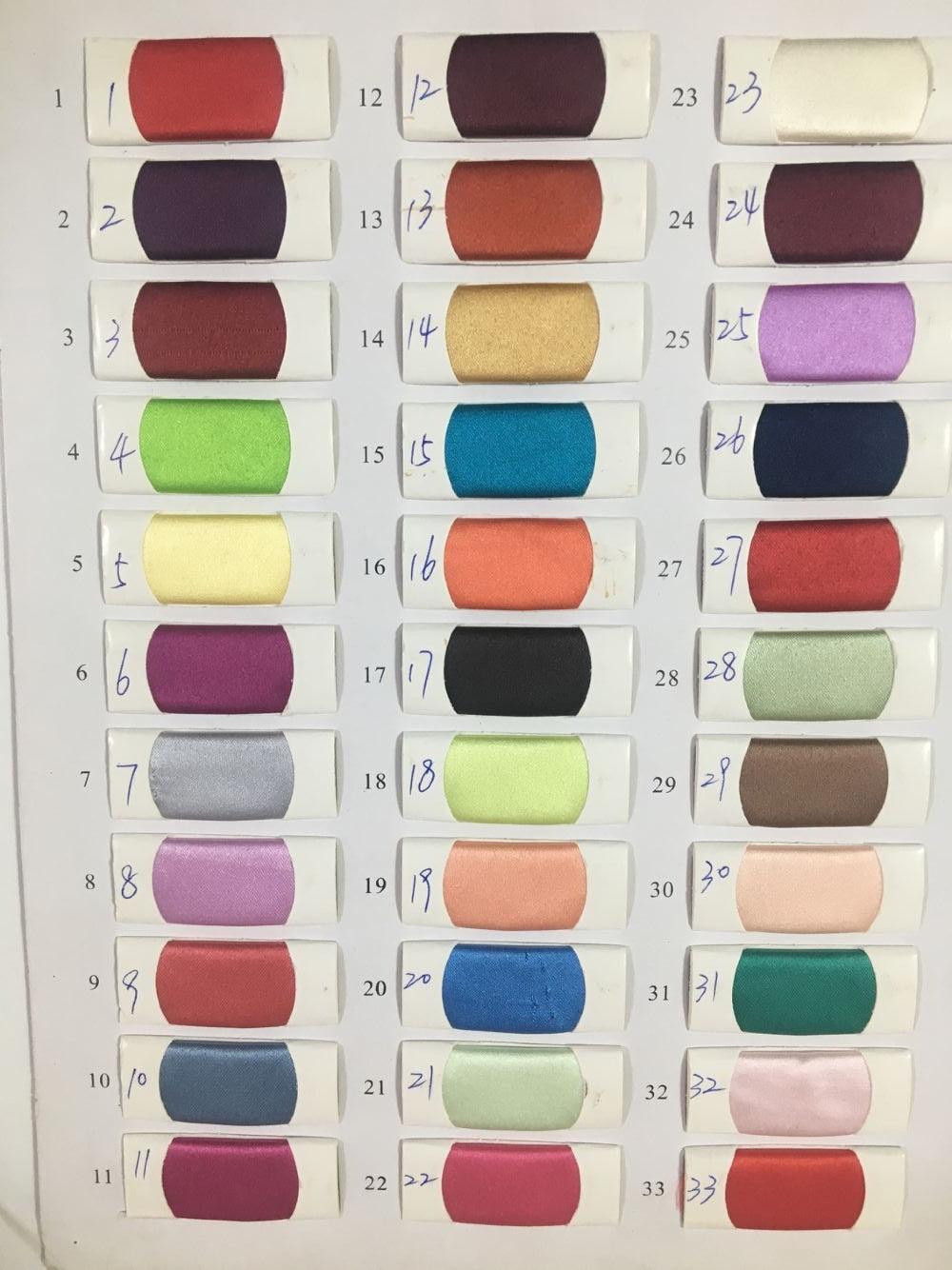 Color chart for Honey Couture formal dresses featuring 33 fabric swatches in various shades for custom gown options.
