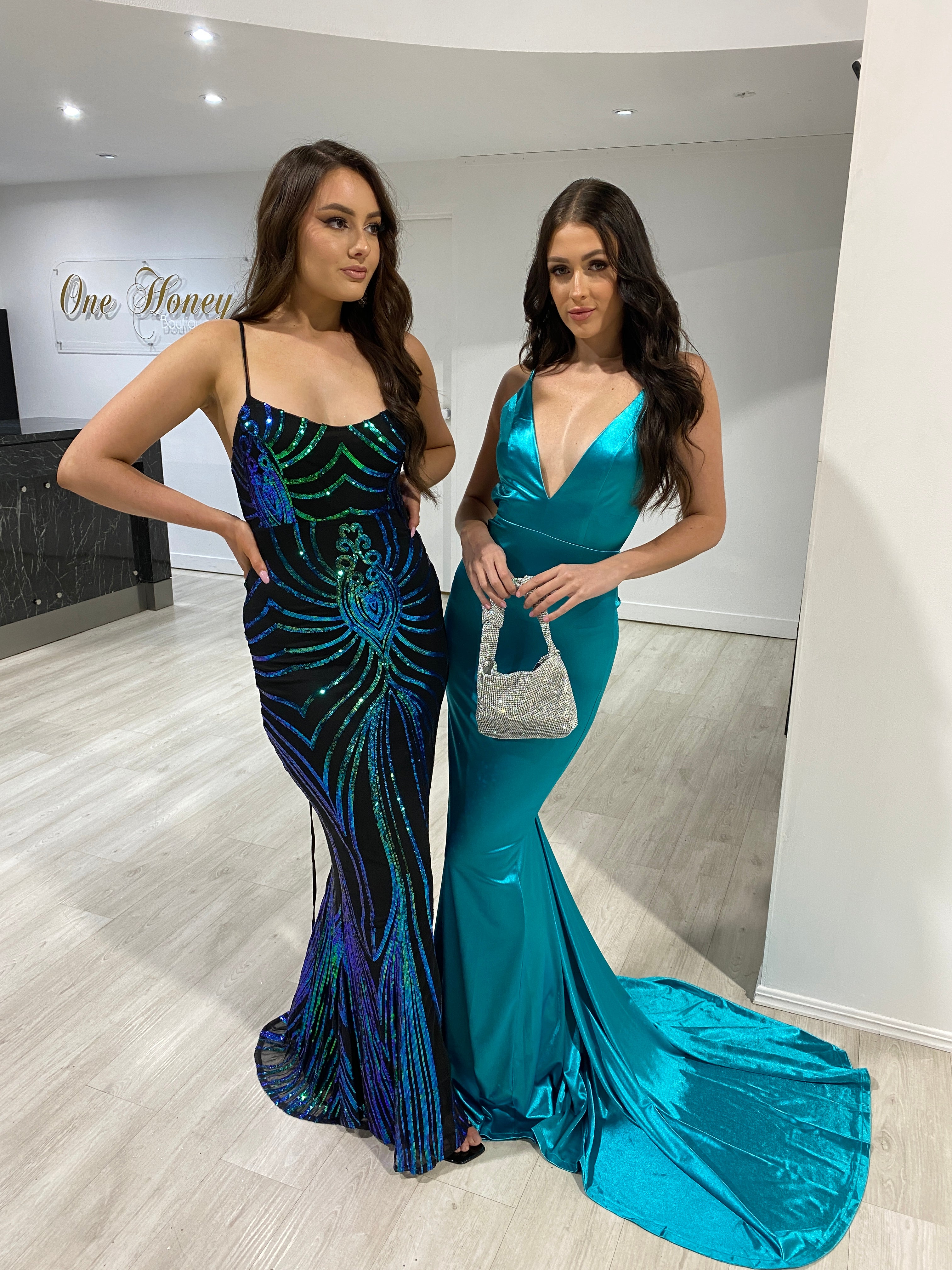 Two women in elegant evening gowns, one in a green and black Honey Couture VERA dress, perfect for prom or formal events.