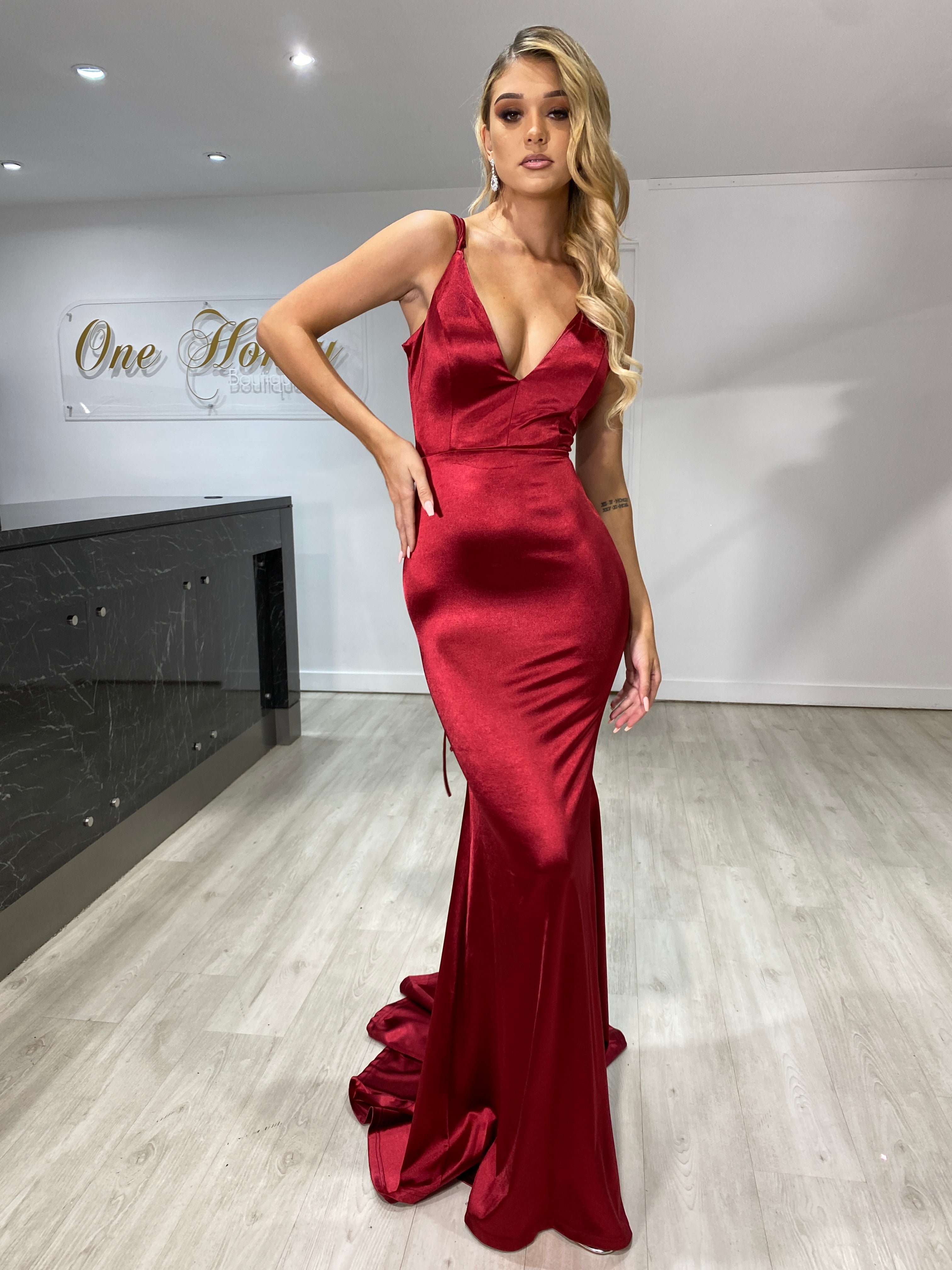 Woman wearing Honey Couture IMOGEN Burgundy Low Back Mermaid Formal Dress, featuring stretch fabric and mermaid train. Perfect for proms.