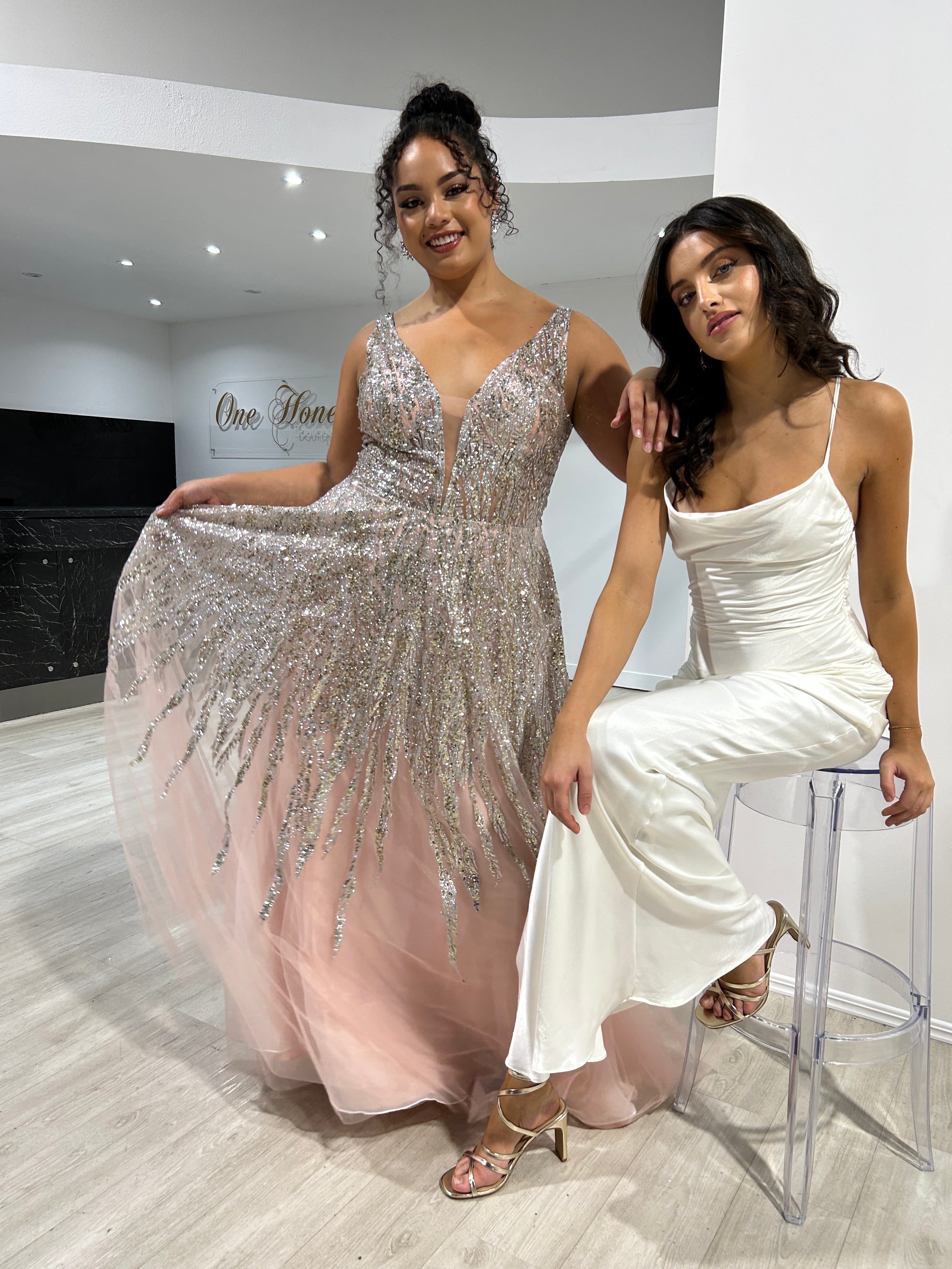 Two models in evening gowns; one in a glittering sequin bodice gown, the other in a sleek satin slip dress. Fashion event, Brisbane to Gold Coast.