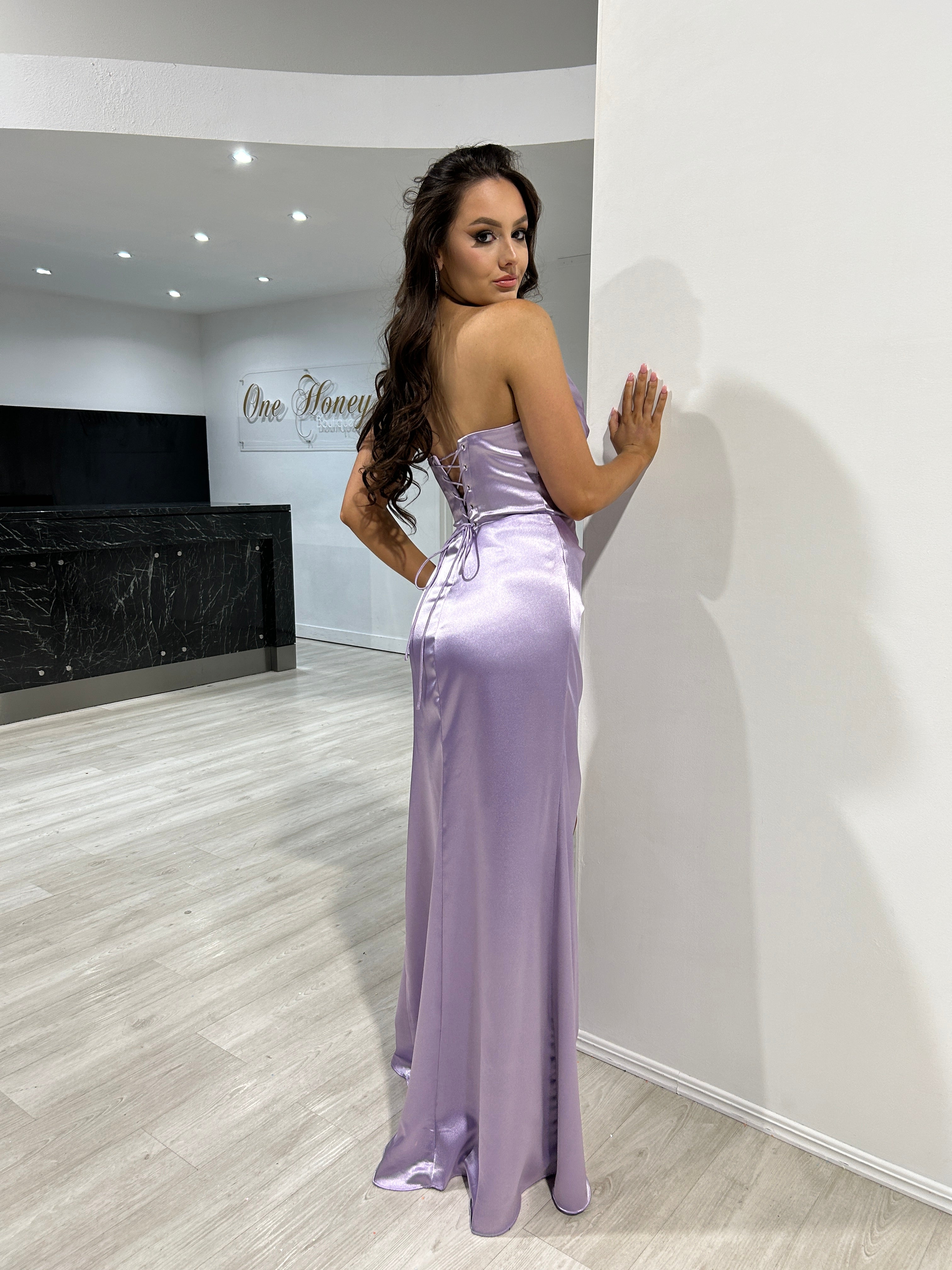 Back view of woman in silky lavender strapless gown standing indoors, showcasing elegant draped design, Brisbane to Gold Coast.