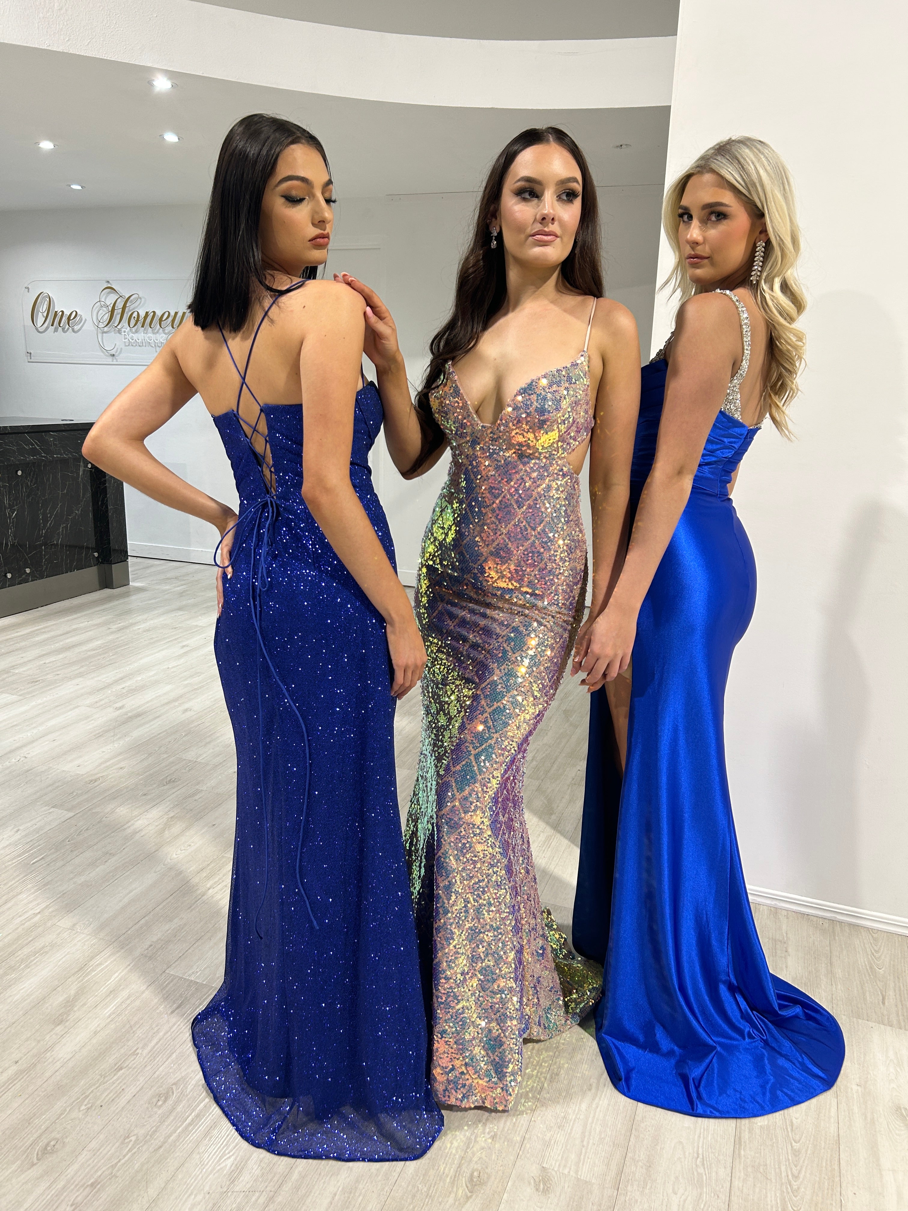 Three women in vibrant blue and sequin mermaid evening gowns by Honey Couture, showcasing Australian designer style for prom or special occasions.