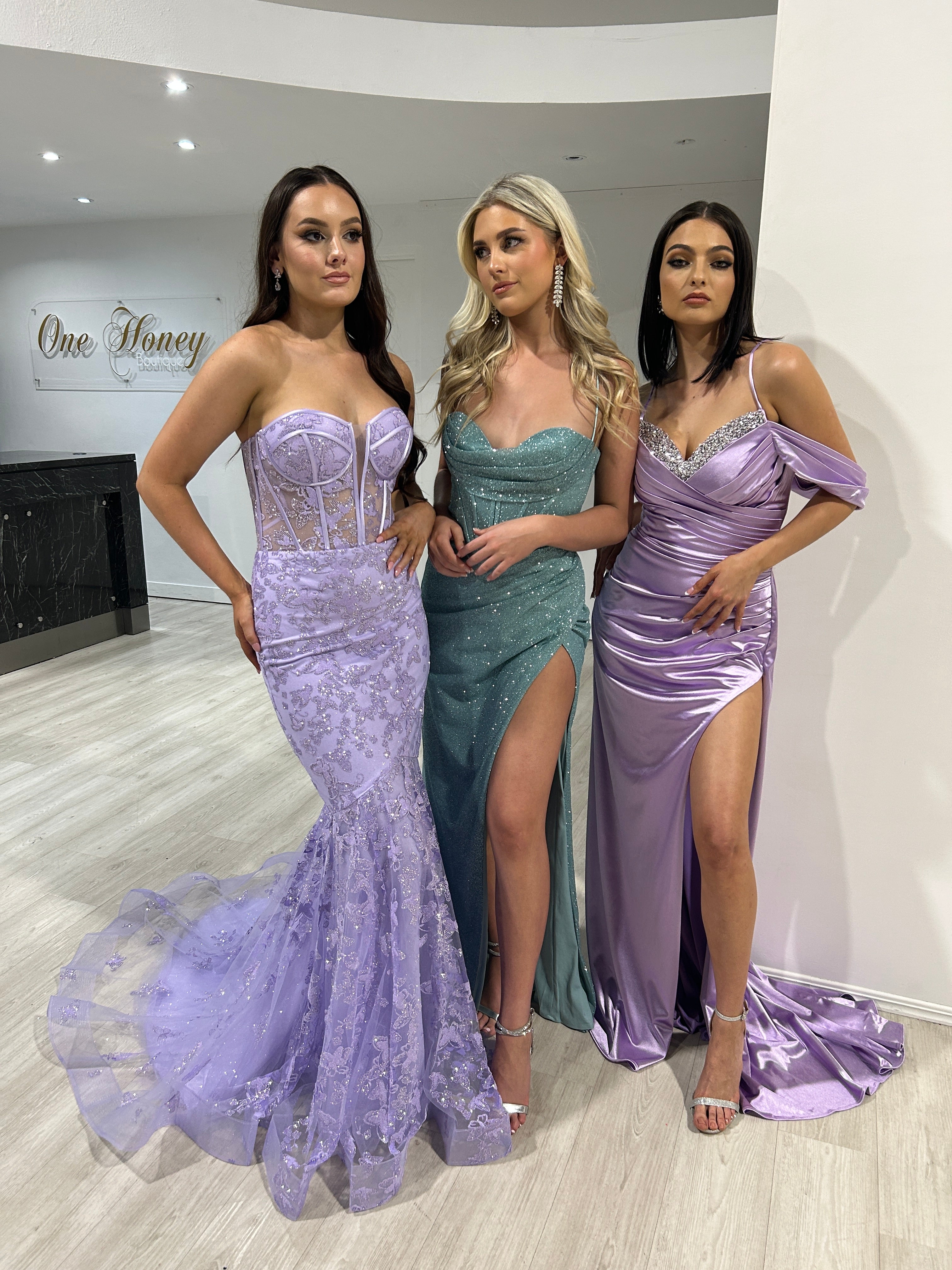 Three women in lilac, teal, and purple silky corset formal gowns with ruched details, perfect for evening glamour. Brisbane to Gold Coast.
