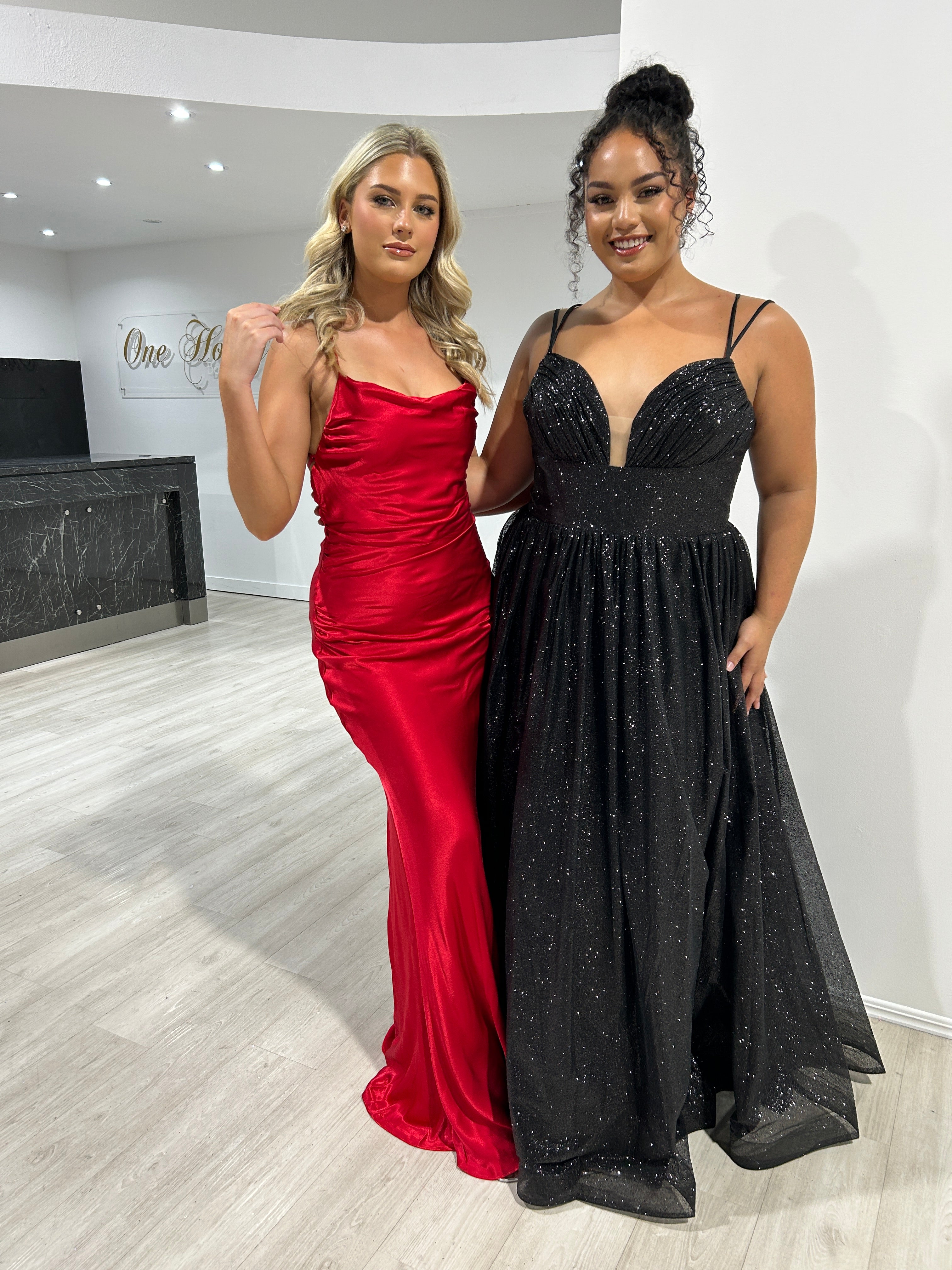 Two women wearing formal gowns; one in a red satin dress, and the other in a black glitter ball gown. Brisbane to Gold Coast, Australia.
