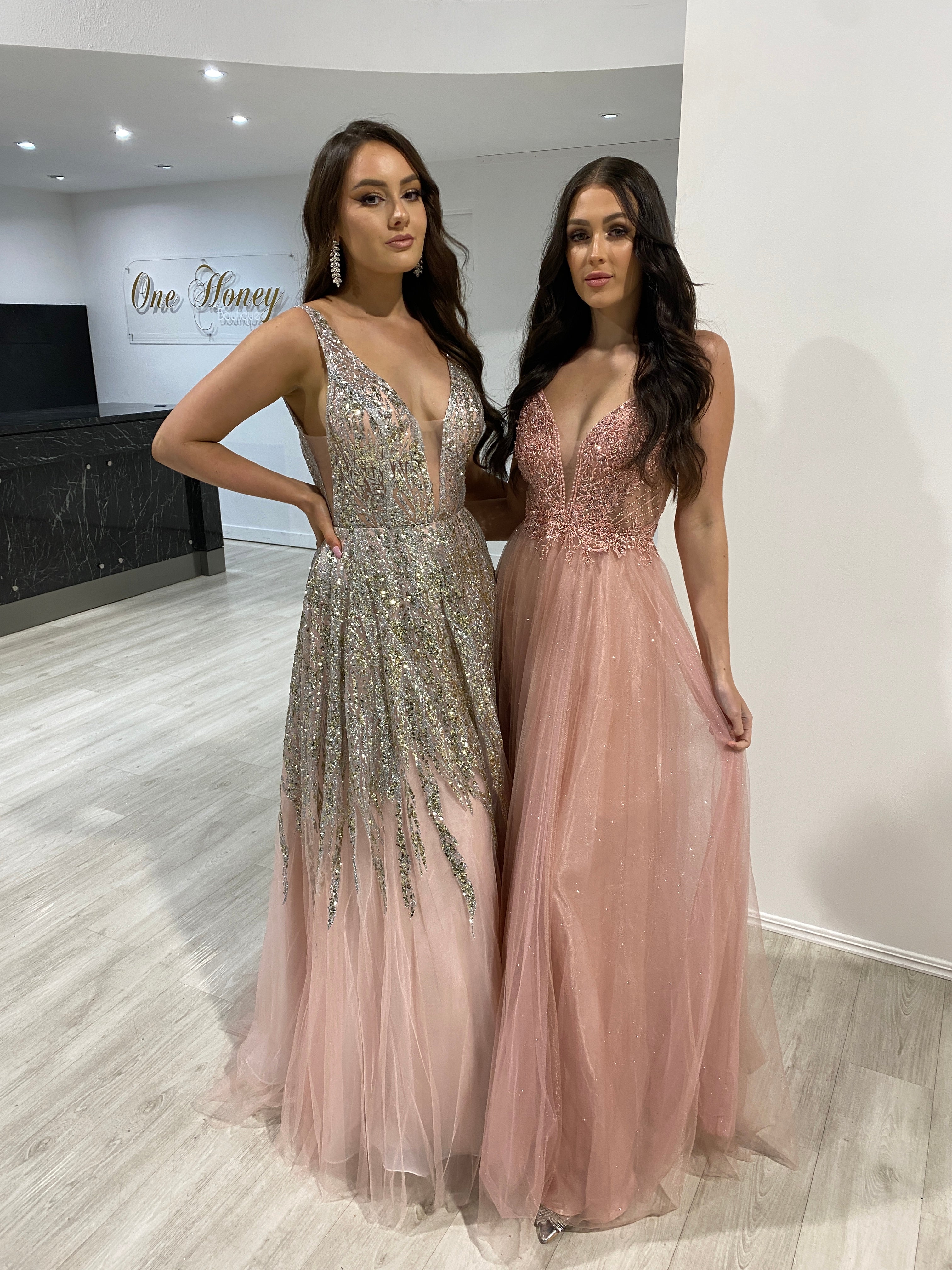 Two women in elegant, beaded applique tulle evening gowns, one in glittering silver, the other in soft pink, indoors. Formal wear fashion showcase. Brisbane to Gold Coast, Australia.