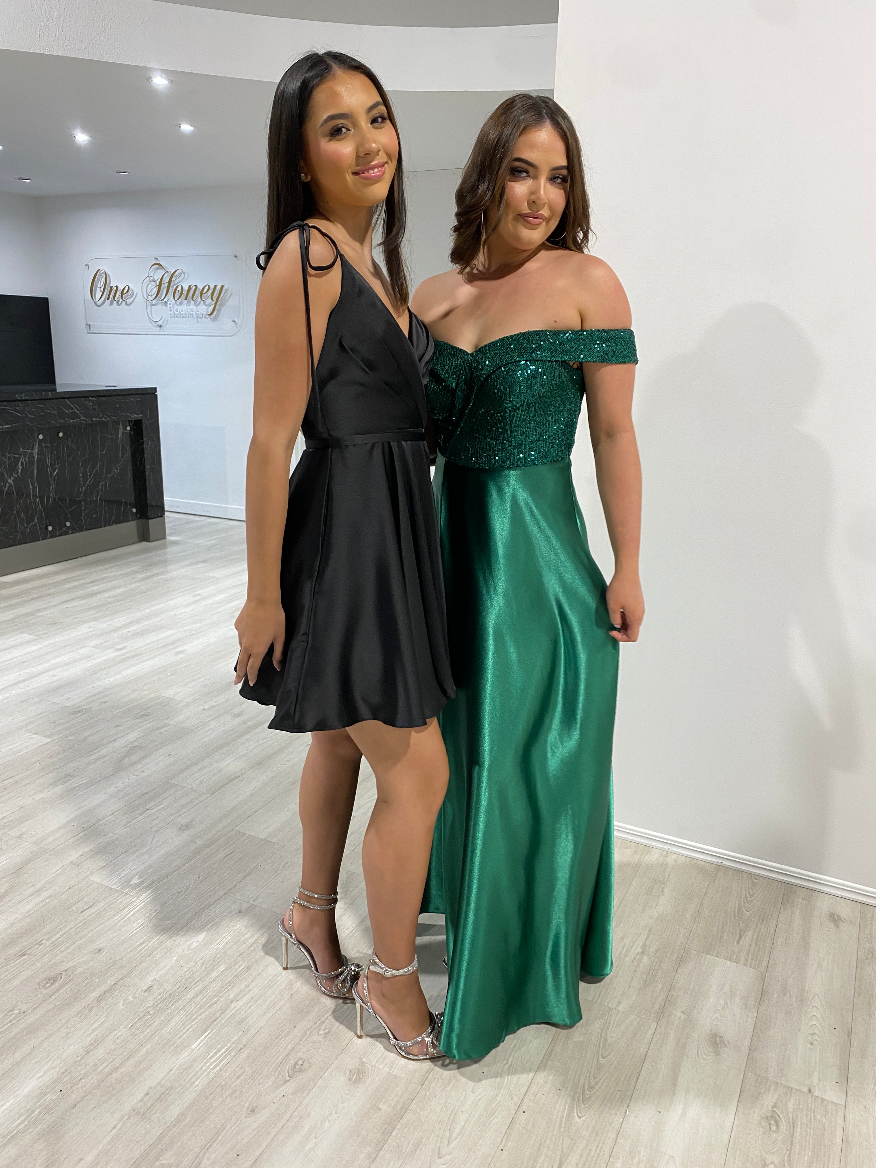 Honey Couture ESTELLA Black Silky Circle Skirt Mini Party Dress on model, paired with a green evening gown, showcasing affordable Australian designer prom dresses.