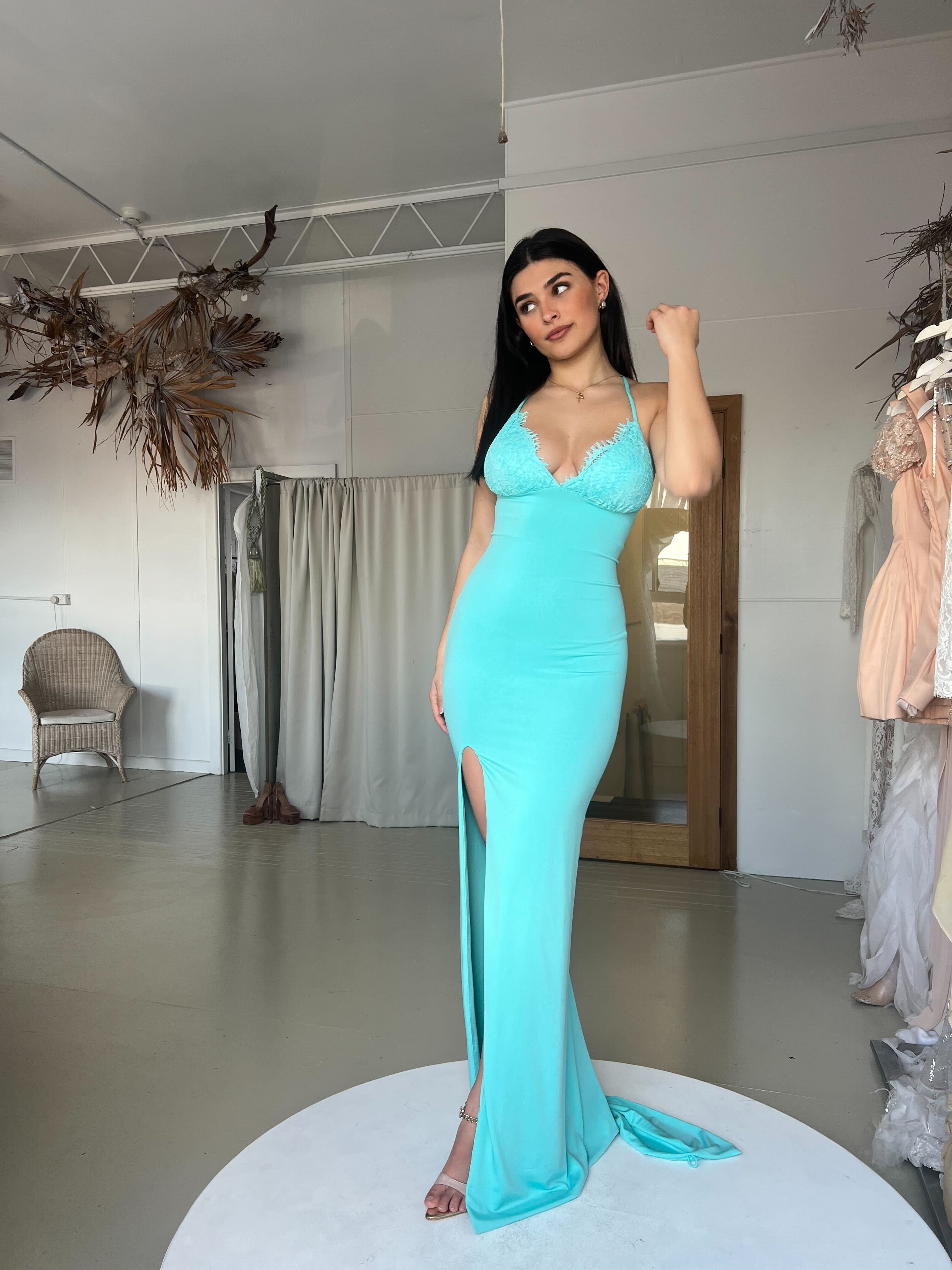 Woman wearing Amy Taylor seafoam blue lace gown with triangle bust, bandage fabric, halter neckline, and leg split, evening wear.